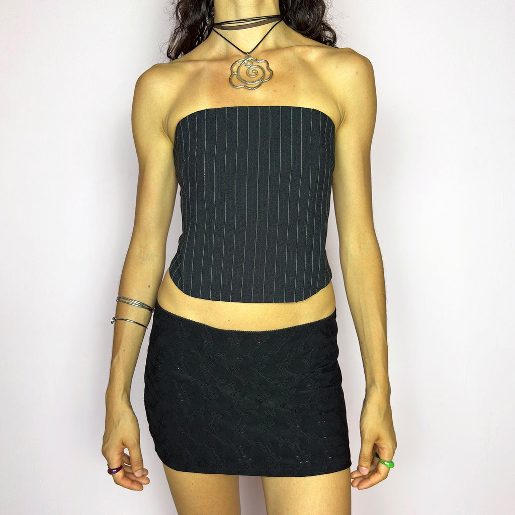 This vintage 2000s pinstripe corset top features a strapless silhouette with boning structure and a back zip closure for a sharp, tailored fit. Crafted in black with fine white stripes, it blends soft tailoring with city girl allure. Elegant yet subversive, it's ideal for cocktail hours, office party nights, or elevated downtown styling. A Y2K structured piece that channels confident, refined edge. Excellent vintage condition.