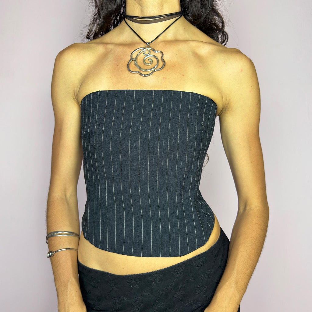 This vintage 2000s pinstripe corset top features a strapless silhouette with boning structure and a back zip closure for a sharp, tailored fit. Crafted in black with fine white stripes, it blends soft tailoring with city girl allure. Elegant yet subversive, it's ideal for cocktail hours, office party nights, or elevated downtown styling. A Y2K structured piece that channels confident, refined edge. Excellent vintage condition.