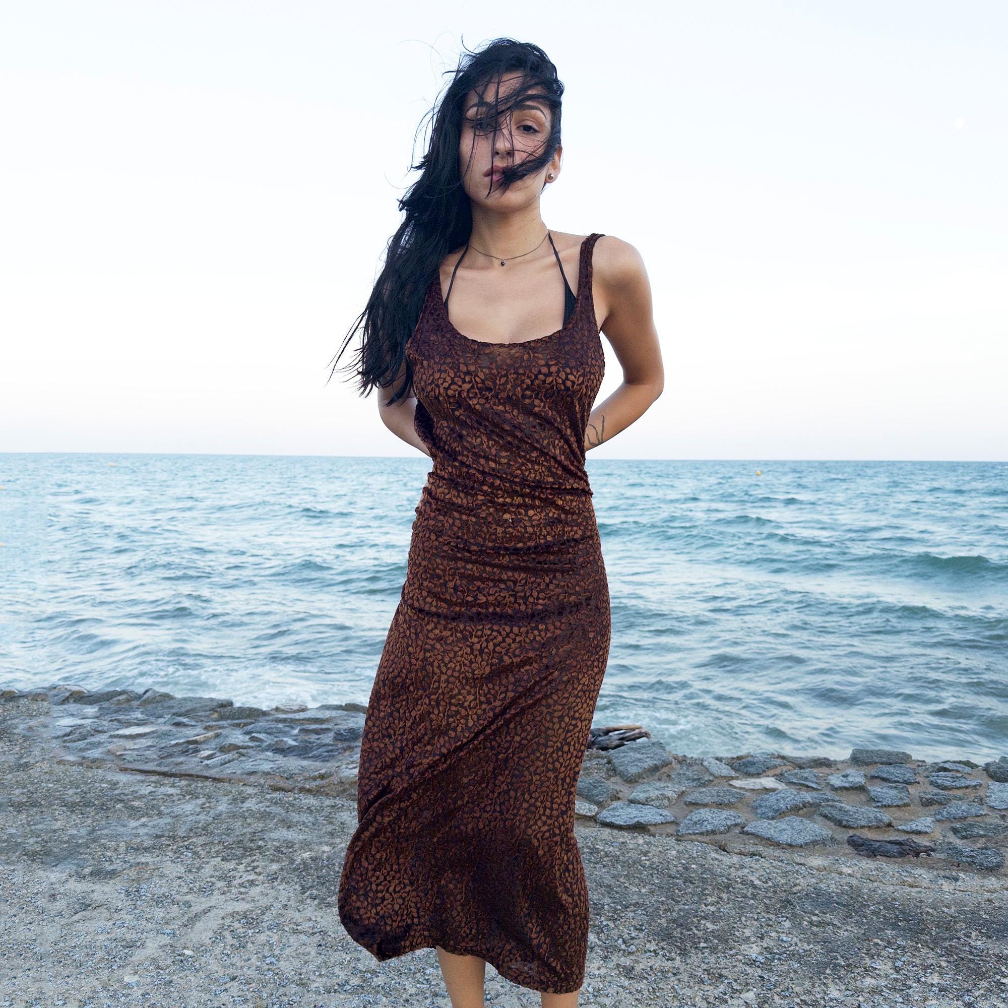 The vintage 90s black midi dress is crafted from sheer devoré velvet with a wild abstract pattern in brown. Sleeveless and fluid, its semi-transparent texture evokes sensual rebellion—ideal for late summer parties, rooftop scenes, or dusk dance floors. A 90s archive dress that blends sensuality and minimalism. Made from a soft, stretchy burnout velvet polyester blend. Great vintage condition.