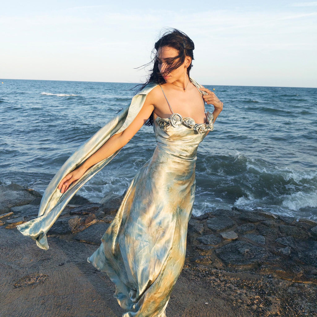 The vintage 2000s pastel tie-dye slip dress is a French-made fantasy in soft blues, greens, and gold. With sculptural rosette appliqué along the bust and a matching scarf, it moves like light on water. The shiny satin-style finish and fluid midi length evoke fairytale softness—ideal for proms, weddings, or summer nights. A romantic Y2K archive crafted from a shimmering non-stretch polyester blend. Great vintage condition.