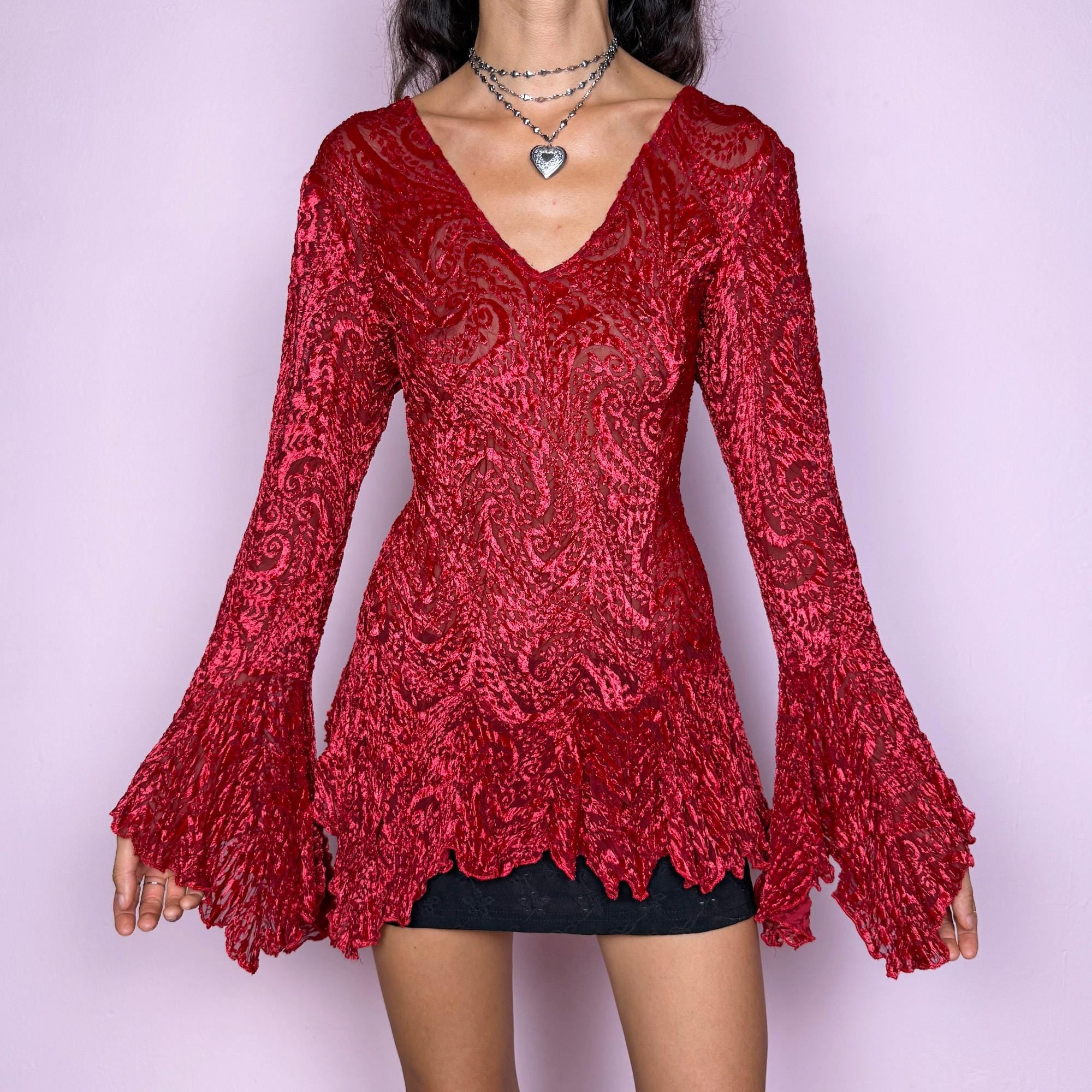 This vintage 2000s top features a dramatic red velvet devoré burnout design with sheer detailing. Styled with asymmetric bell sleeves, a fitted silhouette, and a flared hem, it creates a striking romantic look. Perfect for parties, festivals, or statement evening wear, this Y2K piece captures glamorous gothic energy with artistic flair. A rare archival French design. Made from a stretchy polyester blend devoré velvet. Excellent vintage condition.