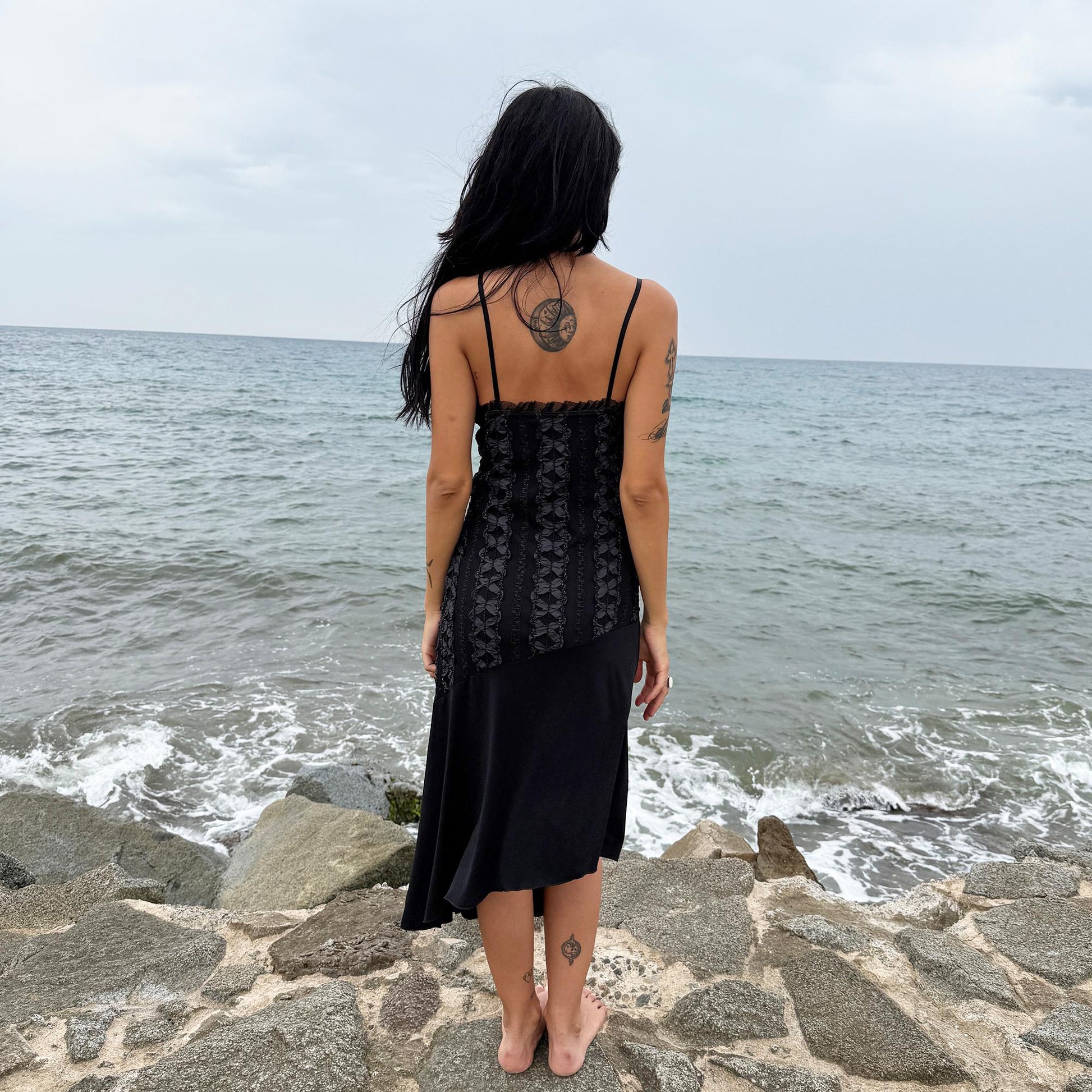 This vintage 2000s black midi dress features an asymmetrical handkerchief hem with whimsical flow and delicate mesh panel details through the bodice. Crafted in France from a stretchy polyester blend, it hugs the figure while allowing movement. A romantic dark piece with fairy, witchy, and night-party energy—perfect for Y2K alternative styling. Made from polyester stretch blend. Excellent vintage condition.