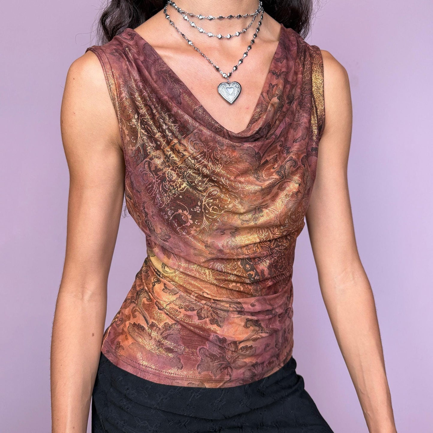 This vintage 2000s sleeveless cowl neck top features a shimmering floral-paisley print in rich, flattering warm bronze, copper, and burgundy tones. The stretchy fabric drapes beautifully, creating a spotlight-ready silhouette ideal for summer nights, parties, or elevated Y2K styling. A collectible archive piece blending romantic detail with glamorous edge. Made from a polyester stretch blend. Made in France. Excellent vintage condition.