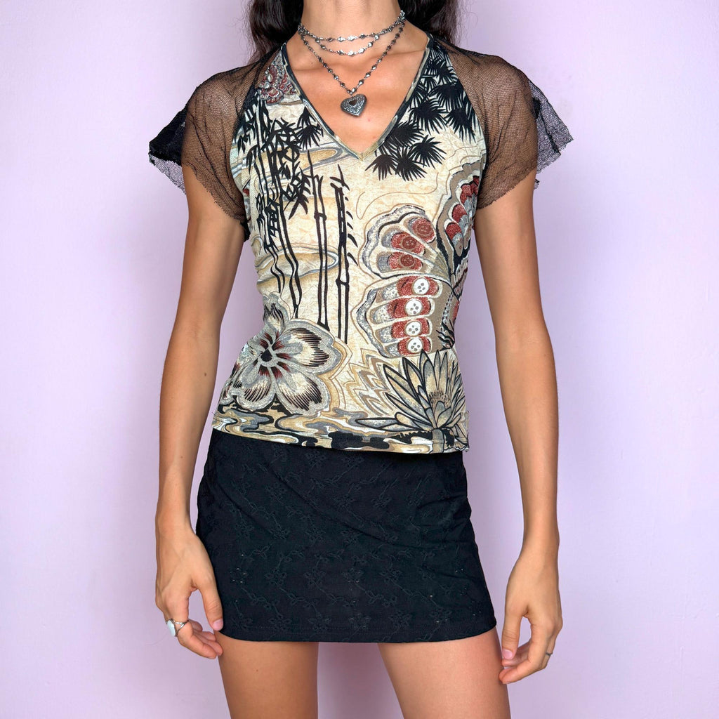 This vintage 2000s top features a bold bamboo and lotus print on the front in cream/beige, black, and rust tones, contrasted by a sheer black lace back with a butterfly pattern. Designed with short mesh sleeves and a fitted cut, this artistic piece is made for after-dark layering or statement summer styling. A rare editorial piece with deconstructed energy. Made from a polyester stretch blend. Excellent vintage condition.