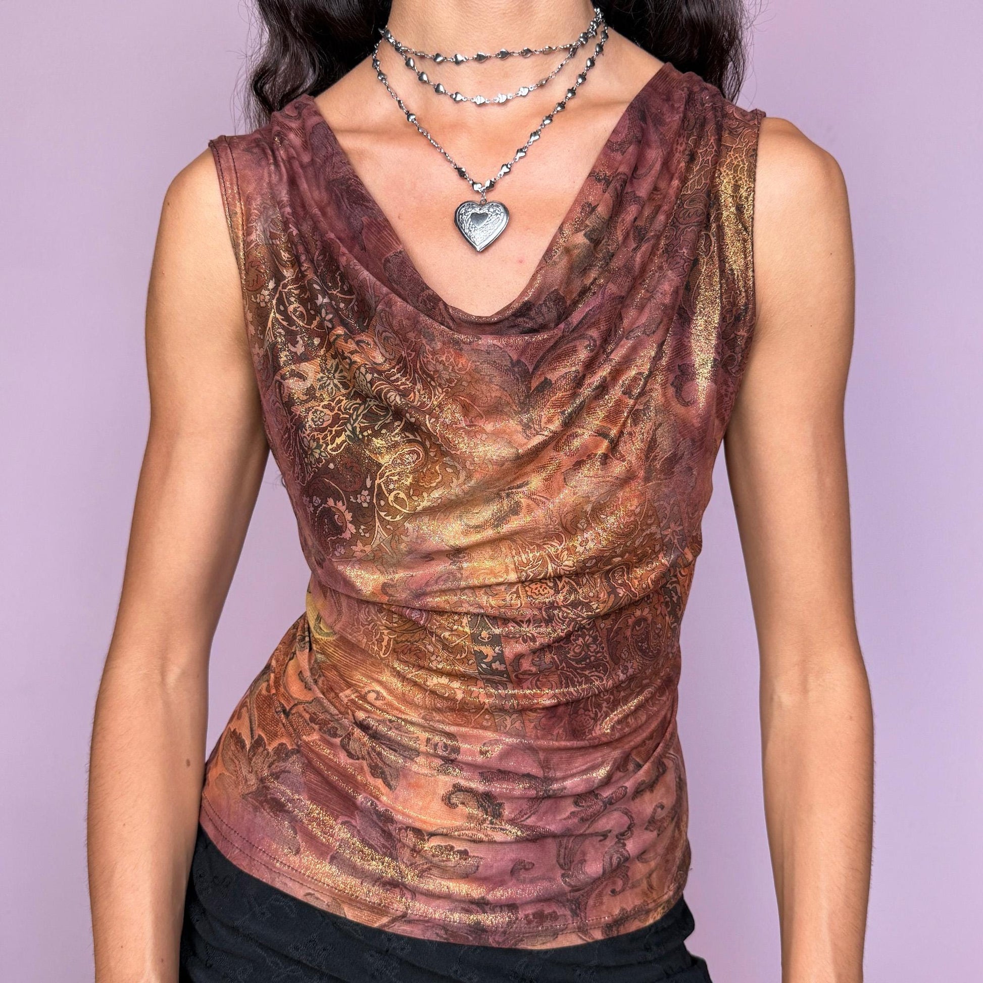 This vintage 2000s sleeveless cowl neck top features a shimmering floral-paisley print in rich, flattering warm bronze, copper, and burgundy tones. The stretchy fabric drapes beautifully, creating a spotlight-ready silhouette ideal for summer nights, parties, or elevated Y2K styling. A collectible archive piece blending romantic detail with glamorous edge. Made from a polyester stretch blend. Made in France. Excellent vintage condition.