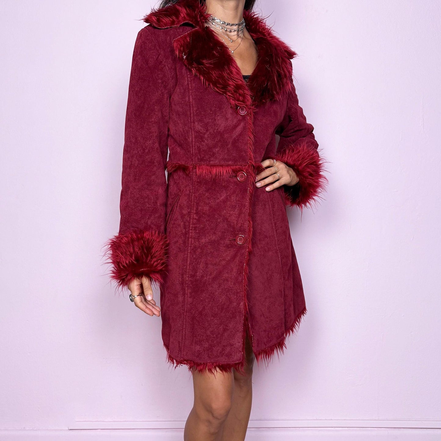 This vintage 2000s dark red Penny Lane coat features plush faux fur trim at the collar and cuffs, front buttons, and side pockets. Made from soft faux suede polyester, it captures glamorous Y2K fairy energy with a bold, whimsical edge. Perfect for winter styling, festivals, or statement nights out. Made from polyester faux suede. Excellent vintage condition.