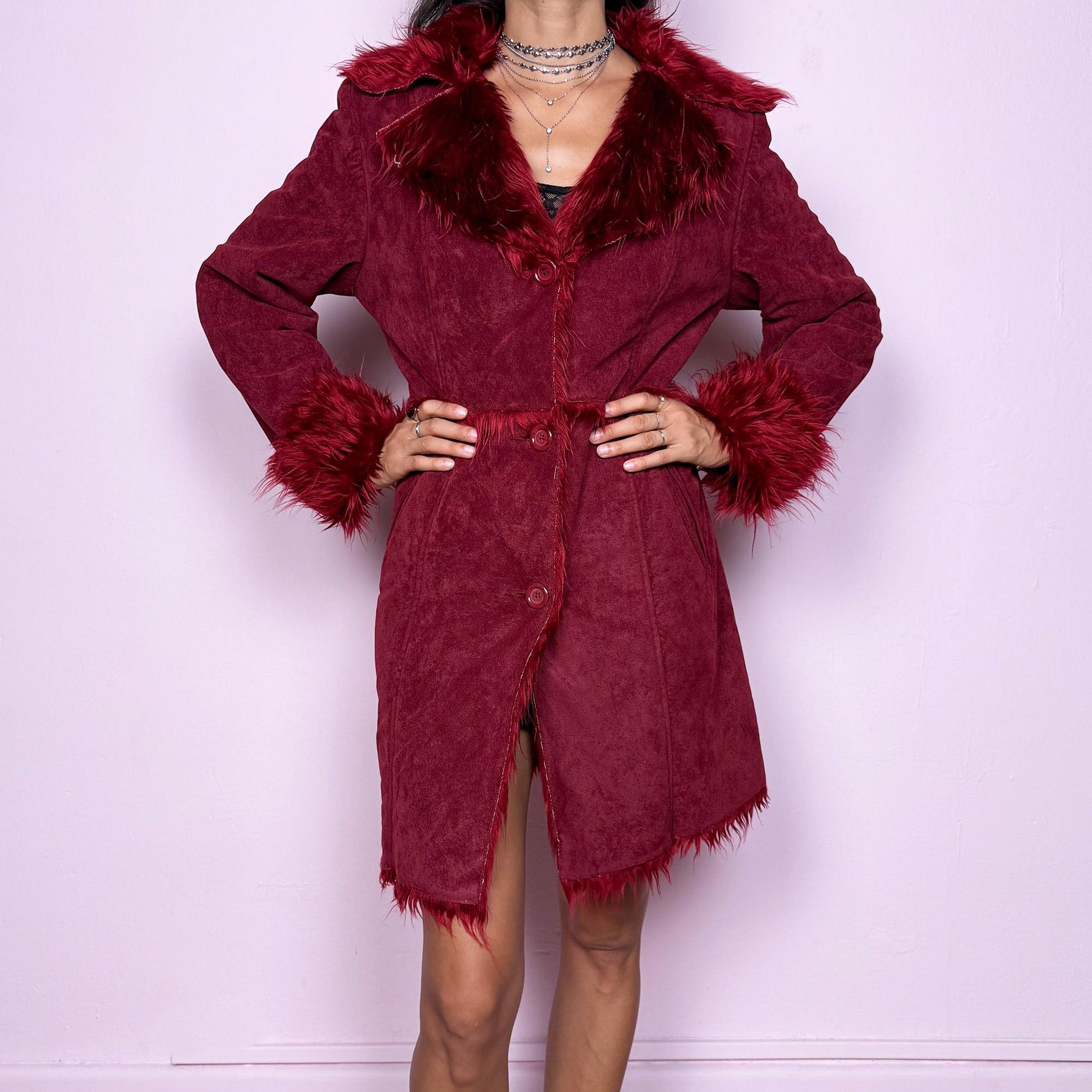 This vintage 2000s dark red Penny Lane coat features plush faux fur trim at the collar and cuffs, front buttons, and side pockets. Made from soft faux suede polyester, it captures glamorous Y2K fairy energy with a bold, whimsical edge. Perfect for winter styling, festivals, or statement nights out. Made from polyester faux suede. Excellent vintage condition.