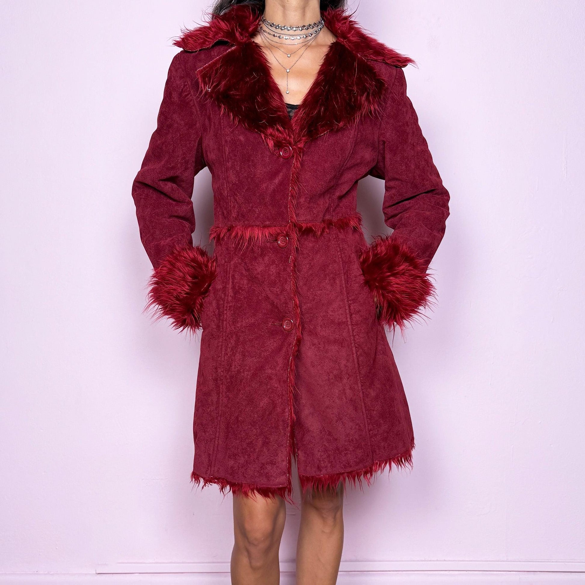 This vintage 2000s dark red Penny Lane coat features plush faux fur trim at the collar and cuffs, front buttons, and side pockets. Made from soft faux suede polyester, it captures glamorous Y2K fairy energy with a bold, whimsical edge. Perfect for winter styling, festivals, or statement nights out. Made from polyester faux suede. Excellent vintage condition.
