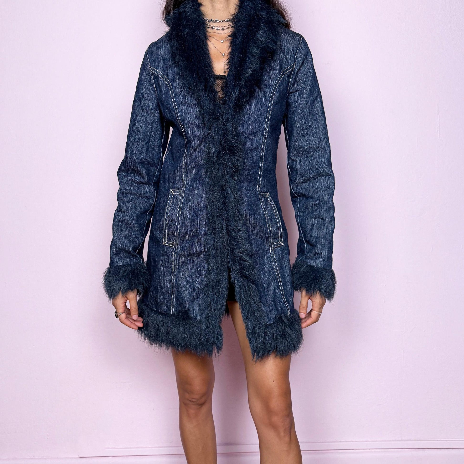 This vintage 2000s dark blue denim Penny Lane coat features deep navy faux fur trim along the collar, cuffs, and hem. Designed with front pockets and button closure, it blends 70s-inspired boho charm with Y2K streetwear edge. The fitted cut and rich indigo tone make it the ultimate statement winter coat—perfect for city styling or retro layering. Made from a cotton polyester denim blend with faux fur trim. Excellent vintage condition.