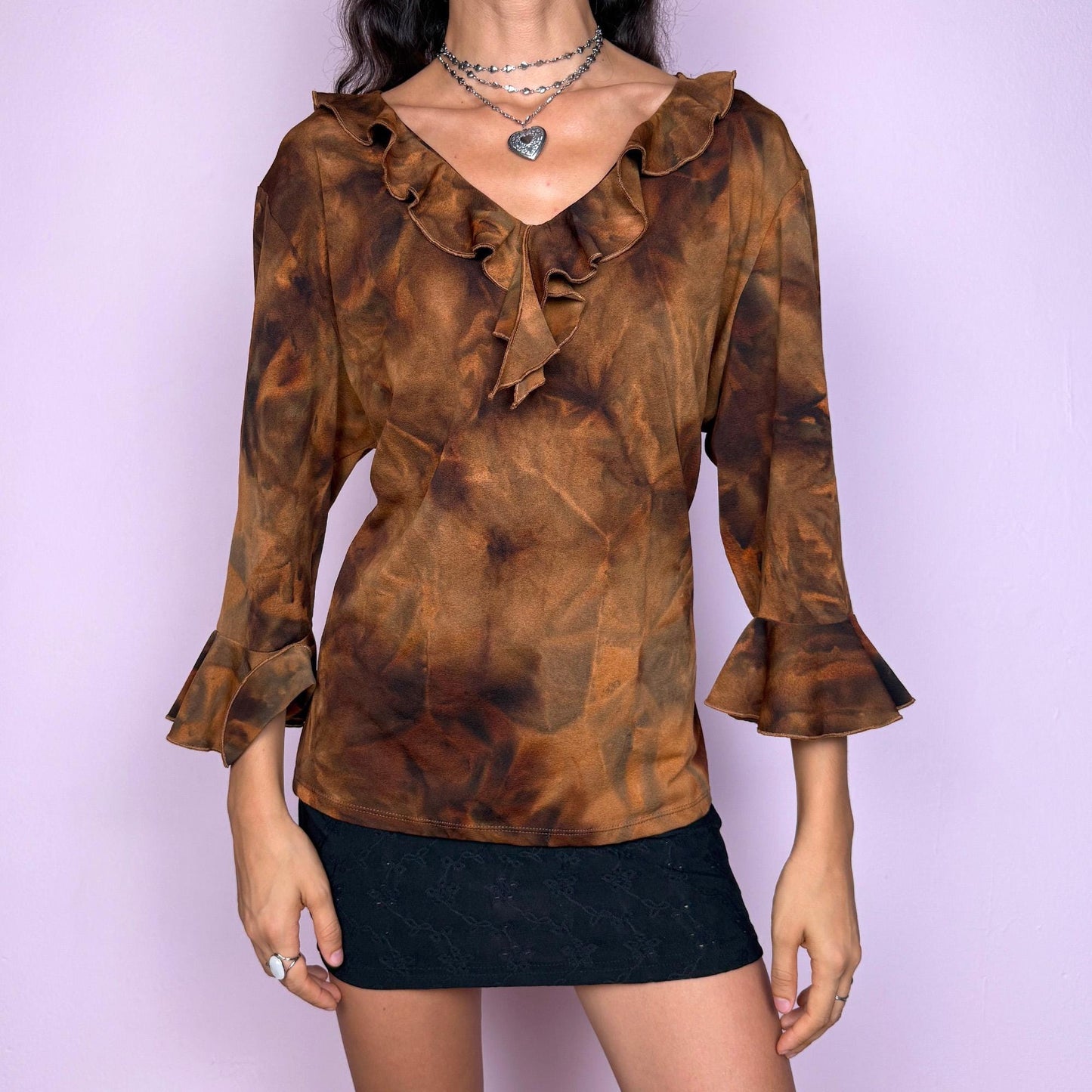 This vintage 2000s brown tie-dye top features a ruffle neckline and three-quarter bell sleeves. Made from stretchy fabric, it channels fairycore with earthy depth and whimsical structure. A perfect piece for boho layering, festival nights, or forest-inspired edits. Made in Spain from a polyester blend. Excellent vintage condition.