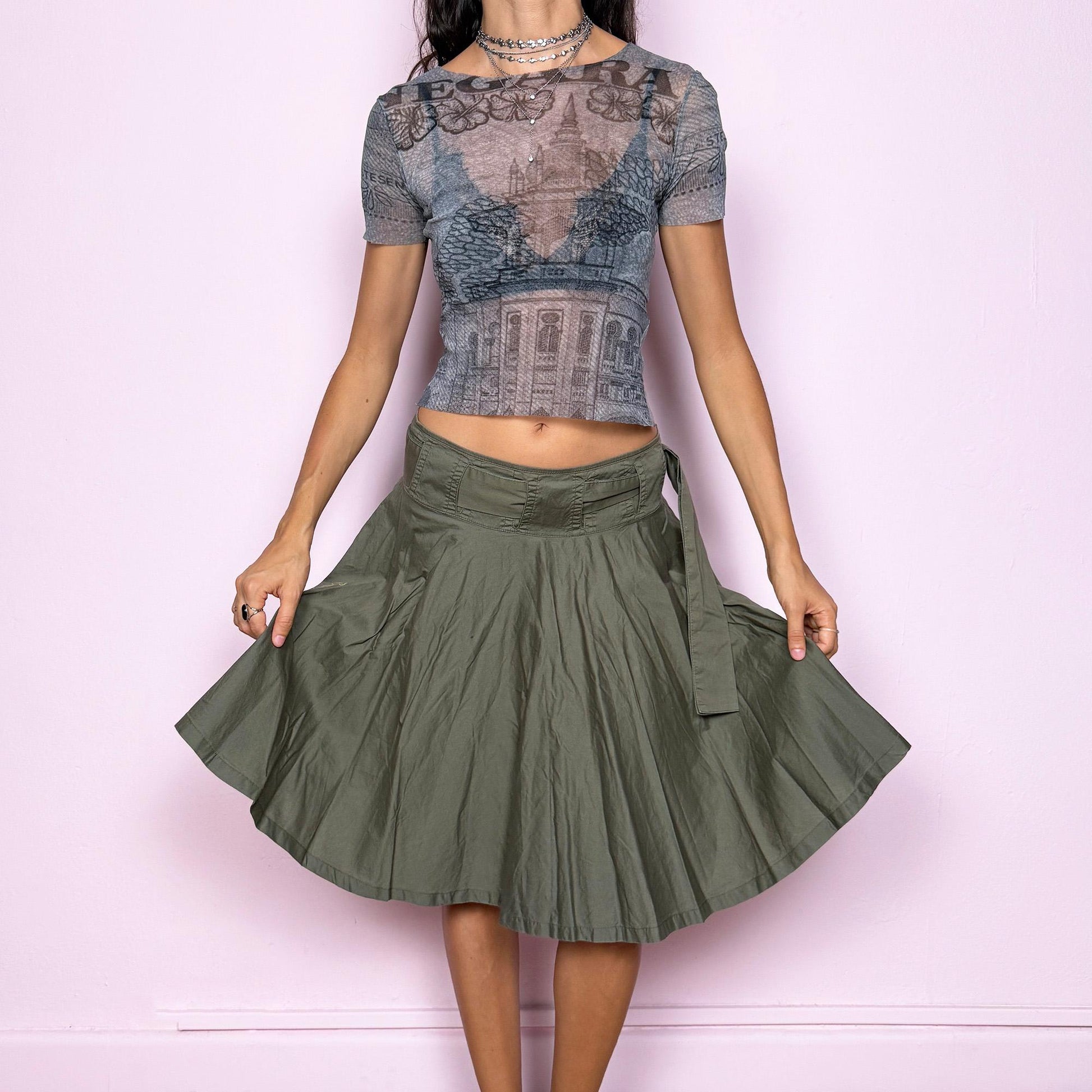 This vintage Y2K khaki green midi skirt features a flared circle silhouette with a side zipper and a removable matching belt that ties elegantly at the side. Designed to sit low-rise, it blends minimalist streetwear with fairycore flow for an effortlessly chic look. Perfect for office wear or summer outings. Made from a soft cotton blend fabric. Excellent vintage condition.