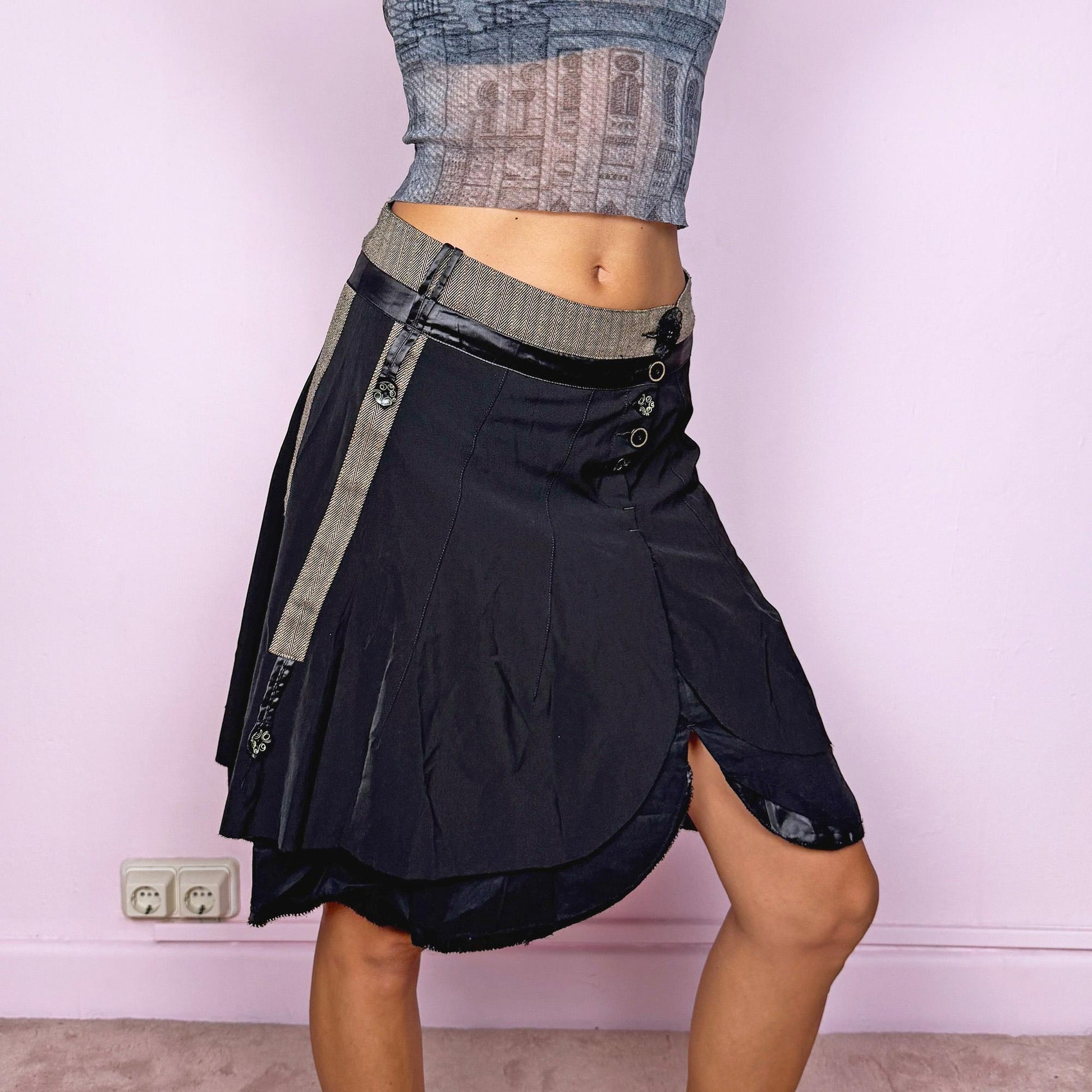 This vintage 2000s black midi skirt features layered panels with a front split and button closure. Its sculptural silhouette combines minimalist elegance with deconstructed avant-garde energy, perfect for formal, artistic, or evening wear. A refined Y2K statement piece that redefines sophistication with edge. Fits size S, worn high-waisted. Great vintage condition.