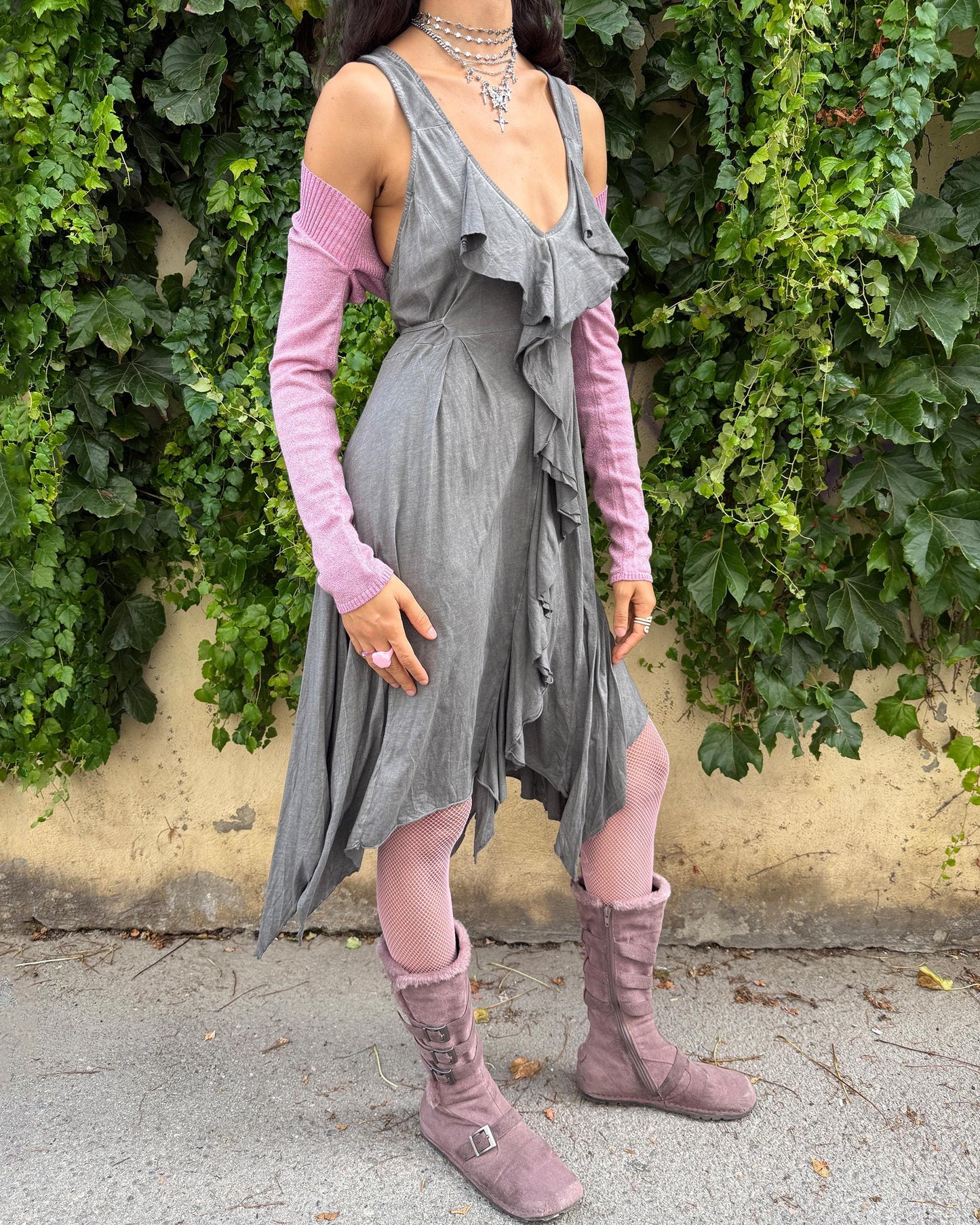 This vintage 2000s gray sleeveless midi dress features a deep V-neckline, cut-out tie back, and cascading ruffles that flow into an asymmetric handkerchief hem. Crafted from soft, stretchy cotton, it embodies whimsical fairycore and deconstructed avant-garde aesthetics in muted tones, perfect for summer layering or artistic styling. Made from 100% cotton fabric. Excellent vintage condition.