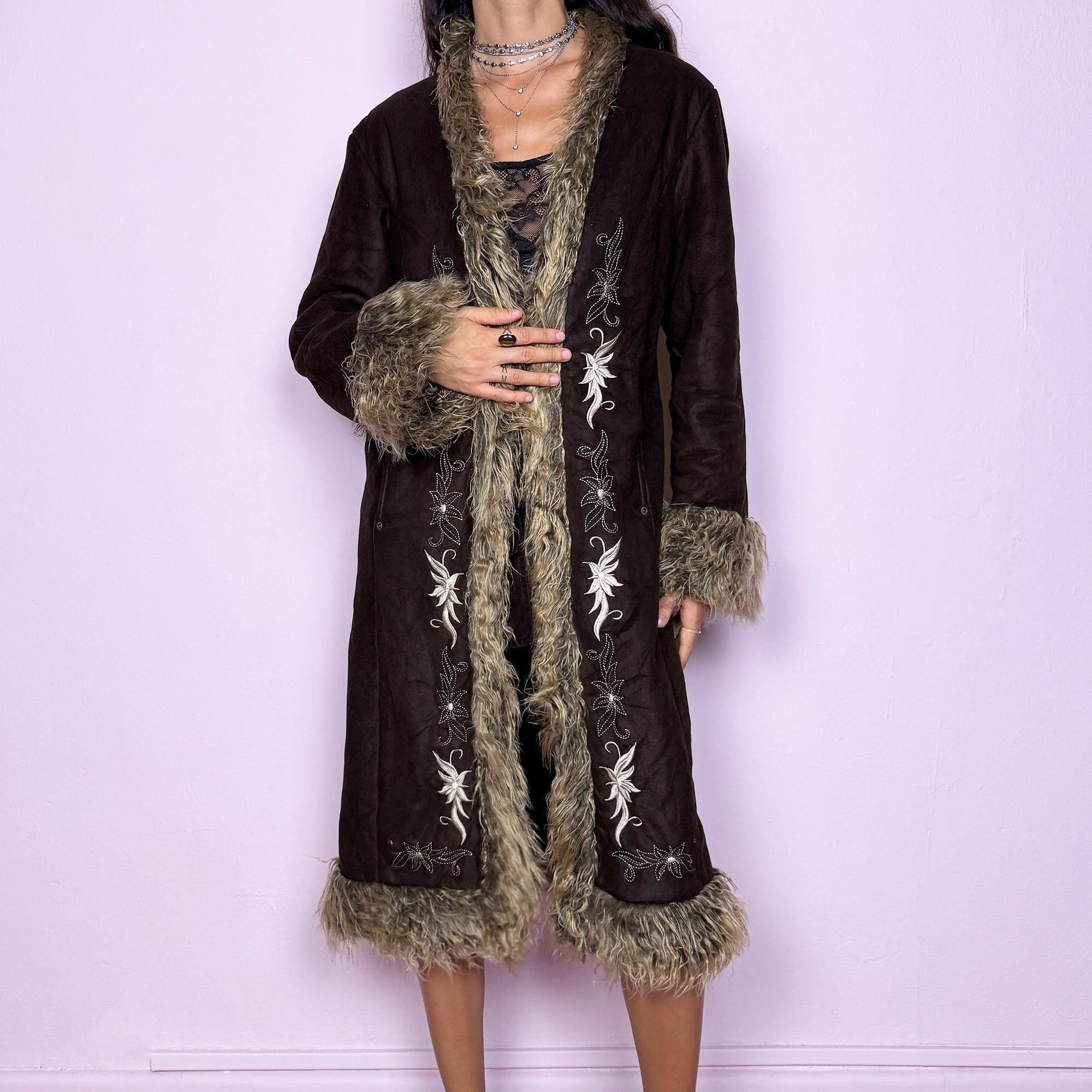 This vintage 2000s dark brown Penny Lane coat features beige faux fur trim at the collar, cuffs, and hem, with intricate floral embroidery along the front. Crafted from soft faux suede with pockets and dual snap-and-hook closure, it embodies the whimsical 70s Afghan-inspired Y2K aesthetic. Warm and romantic—perfect for fairycore, boho, and forest muse styling. Made from polyester faux suede and faux fur. Great vintage condition.