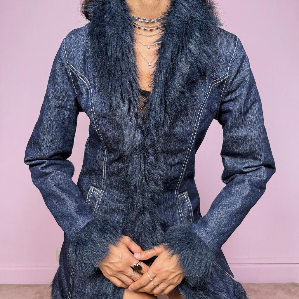 This vintage 2000s dark blue denim Penny Lane coat features deep navy faux fur trim along the collar, cuffs, and hem. Designed with front pockets and button closure, it blends 70s-inspired boho charm with Y2K streetwear edge. The fitted cut and rich indigo tone make it the ultimate statement winter coat—perfect for city styling or retro layering. Made from a cotton polyester denim blend with faux fur trim. Excellent vintage condition.