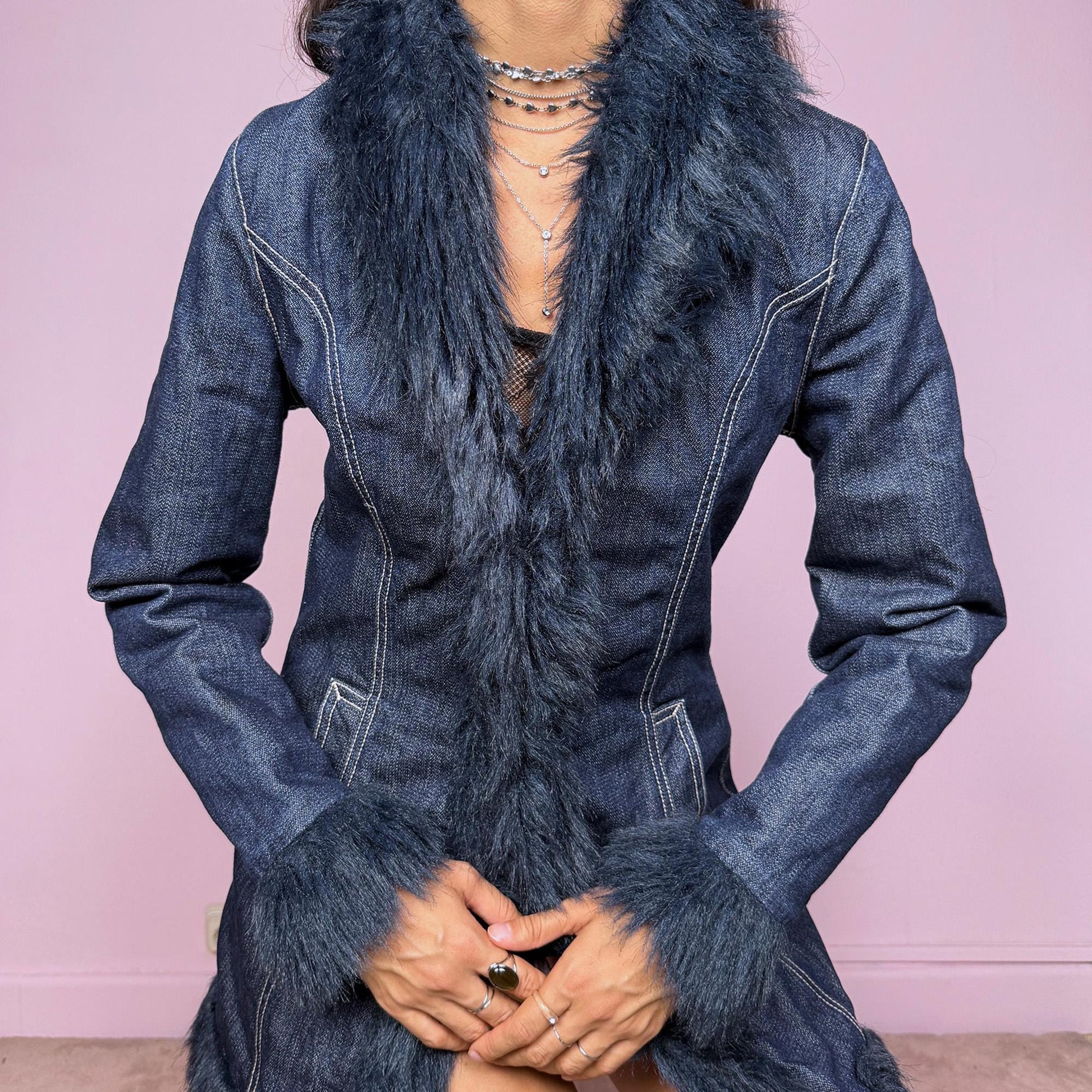 This vintage 2000s dark blue denim Penny Lane coat features deep navy faux fur trim along the collar, cuffs, and hem. Designed with front pockets and button closure, it blends 70s-inspired boho charm with Y2K streetwear edge. The fitted cut and rich indigo tone make it the ultimate statement winter coat—perfect for city styling or retro layering. Made from a cotton polyester denim blend with faux fur trim. Excellent vintage condition.