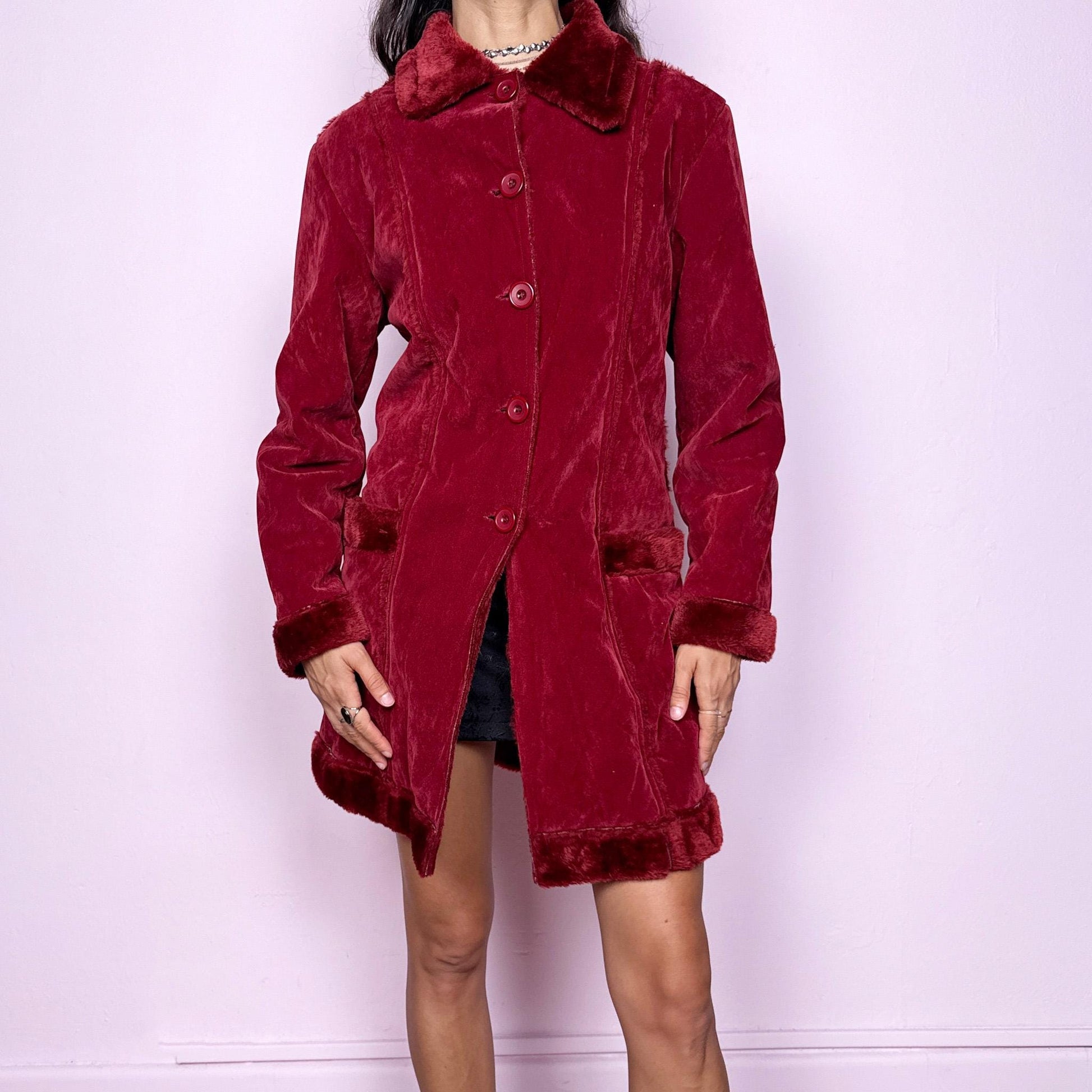 This vintage 2000s red faux suede coat features a plush faux fur lining, collar, and cuffs inspired by the iconic Penny Lane silhouette. Designed with front pockets and button closure, it captures whimsical Y2K winter charm with a boho-grunge edge, perfect for festivals or statement cold-weather styling. Made from polyester faux suede and faux fur. Great vintage condition.
