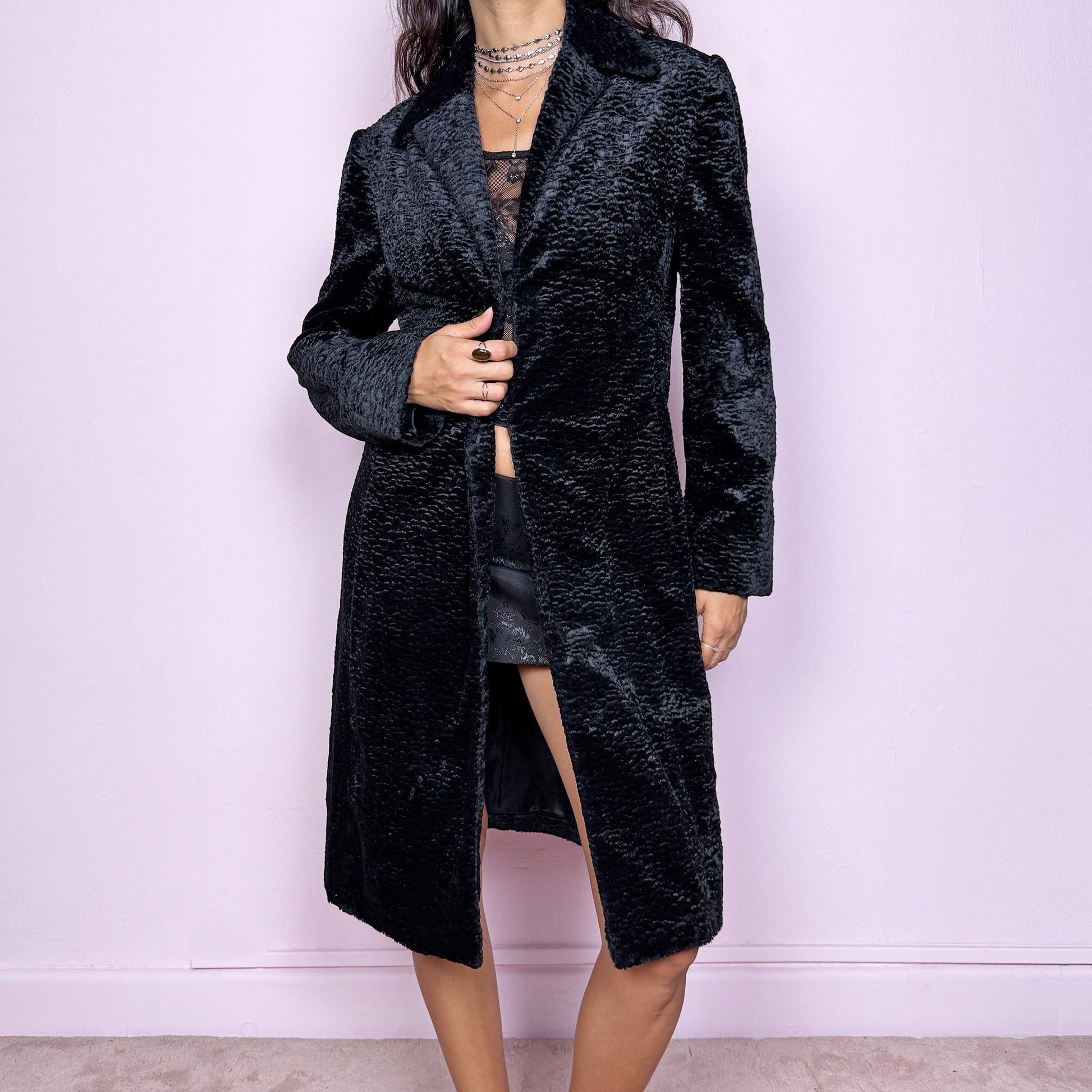 This vintage 2000s black faux fur collared coat features a structured silhouette with shoulder pads, two hook closures, and side pockets. Luxuriously soft and tailored, it’s perfect for formal nights, office wear, or elegant events such as galas or bridal occasions. A timeless classic made from a cotton, polyester, and viscose blend. Great vintage condition.