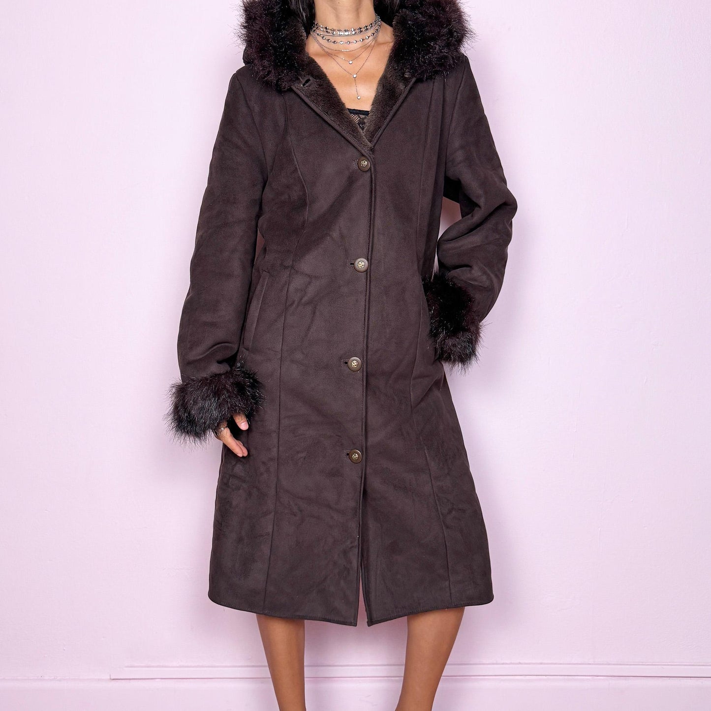This stunning vintage 2000s dark brown-purple faux suede long coat features a hooded Penny Lane cut with a plush faux fur collar, cuffs, and full interior. It also includes a button front and pockets. Its rich tone evokes dark whimsy and fairycore night energy, blending goth romance with bohemian warmth. Made from faux suede with faux fur lining. Great vintage condition.