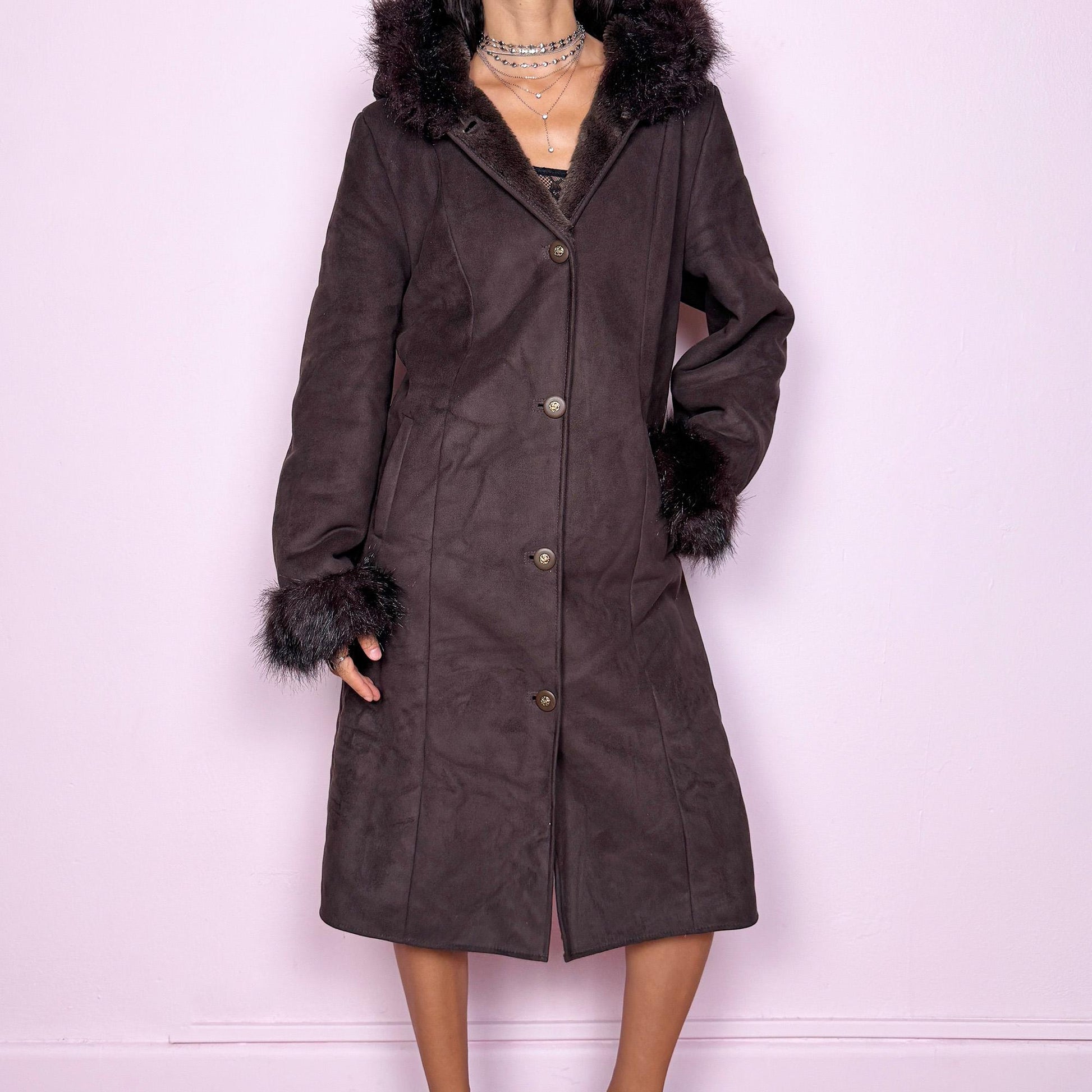 This stunning vintage 2000s dark brown-purple faux suede long coat features a hooded Penny Lane cut with a plush faux fur collar, cuffs, and full interior. It also includes a button front and pockets. Its rich tone evokes dark whimsy and fairycore night energy, blending goth romance with bohemian warmth. Made from faux suede with faux fur lining. Great vintage condition.