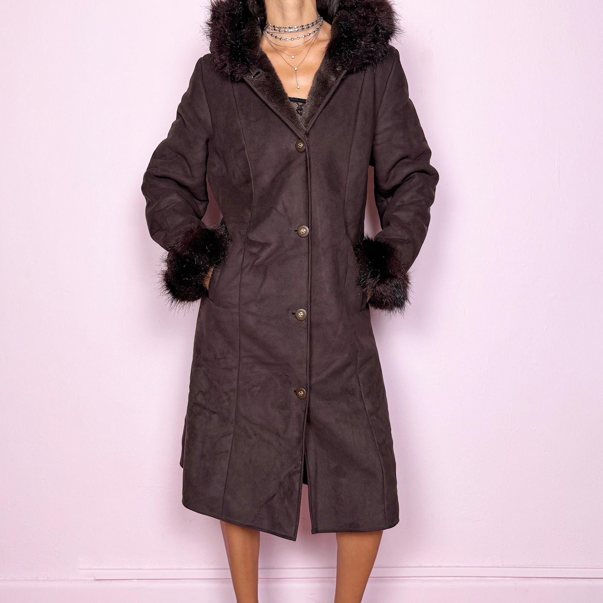 This stunning vintage 2000s dark brown-purple faux suede long coat features a hooded Penny Lane cut with a plush faux fur collar, cuffs, and full interior. It also includes a button front and pockets. Its rich tone evokes dark whimsy and fairycore night energy, blending goth romance with bohemian warmth. Made from faux suede with faux fur lining. Great vintage condition.