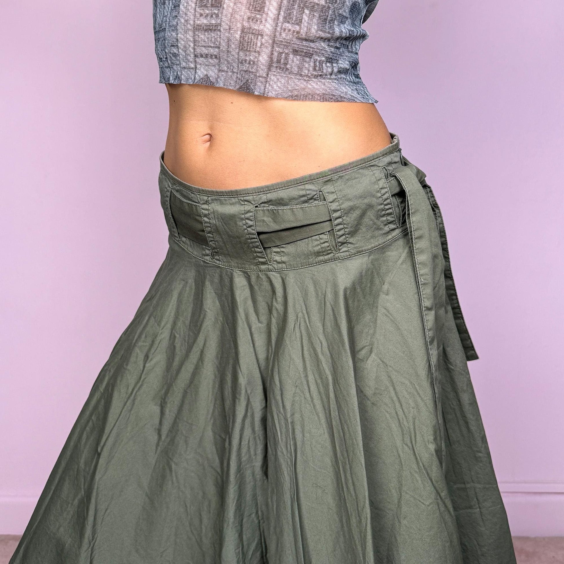 This vintage Y2K khaki green midi skirt features a flared circle silhouette with a side zipper and a removable matching belt that ties elegantly at the side. Designed to sit low-rise, it blends minimalist streetwear with fairycore flow for an effortlessly chic look. Perfect for office wear or summer outings. Made from a soft cotton blend fabric. Excellent vintage condition.