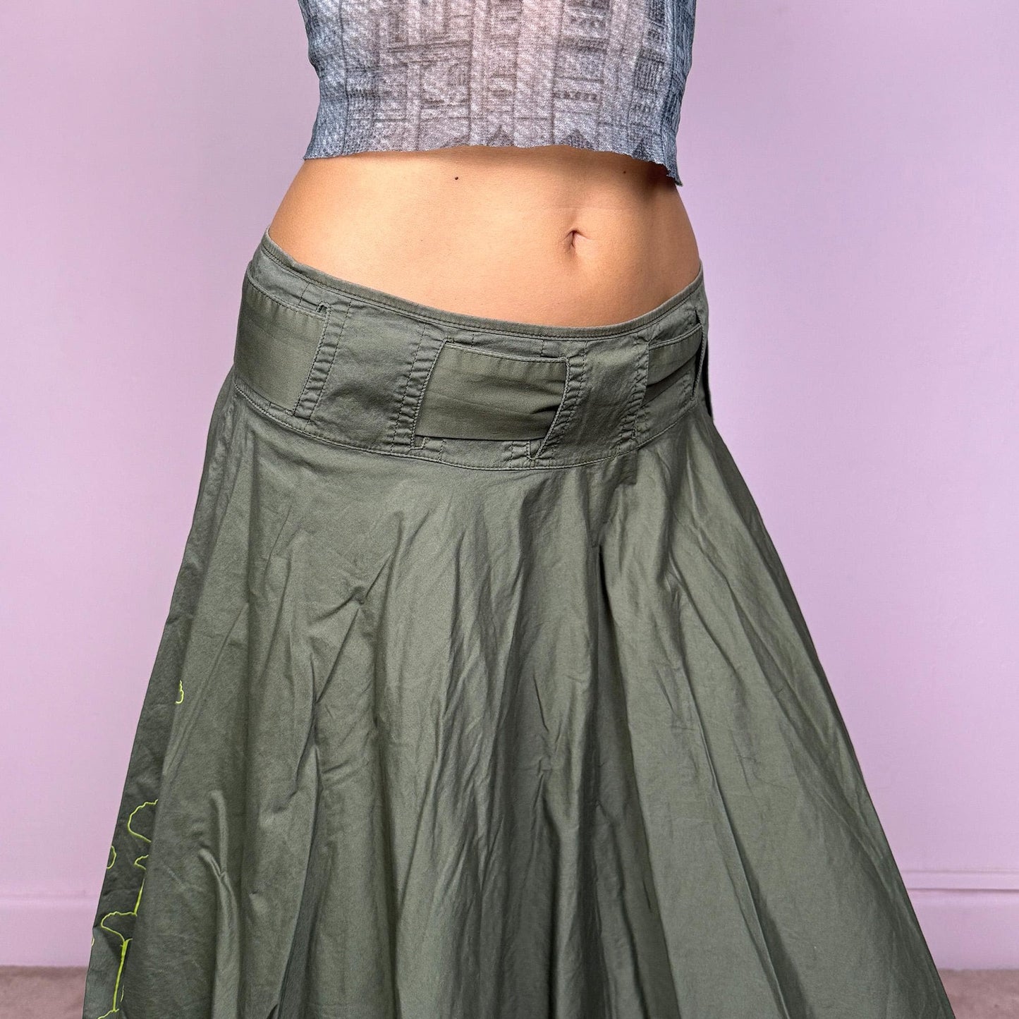This vintage Y2K khaki green midi skirt features a flared circle silhouette with a side zipper and a removable matching belt that ties elegantly at the side. Designed to sit low-rise, it blends minimalist streetwear with fairycore flow for an effortlessly chic look. Perfect for office wear or summer outings. Made from a soft cotton blend fabric. Excellent vintage condition.