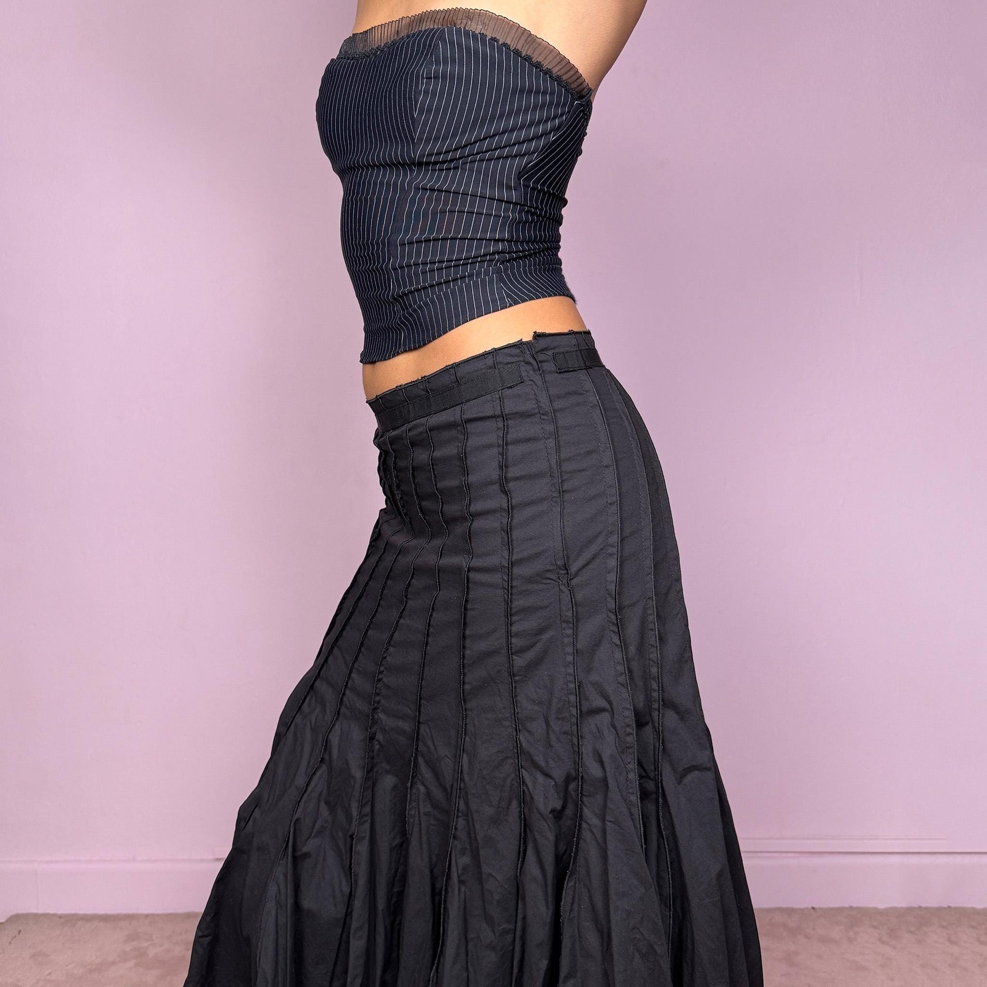 This vintage 2000s black paneled midi skirt features a structured godet flare hem and side zipper closure. Slightly stretchy with a refined drape, it can be worn high-rise for size S or mid-rise for size XS. A stunning French-made piece ideal for formal nights, office wear, or elegant parties. Made in France from a cotton lycra blend. Excellent vintage condition.