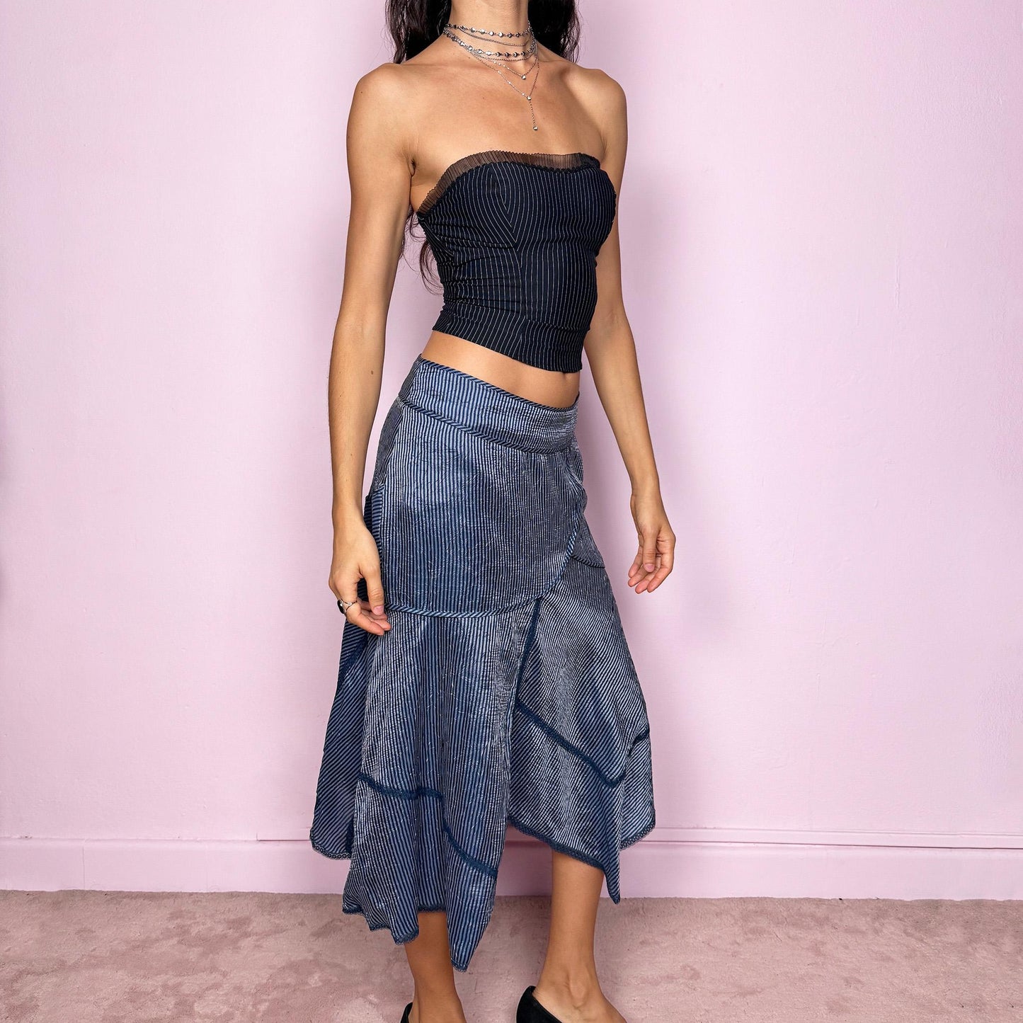 This vintage 2000s blue striped patchwork midi skirt features an asymmetric hemline, delicate lace trim details, and a side zipper closure. Lightweight and non-stretch, it offers a breezy, formal look ideal for summer styling. Can be worn low-rise for size XS or mid-rise for size S, creating an elegant and modern silhouette. Excellent vintage condition.