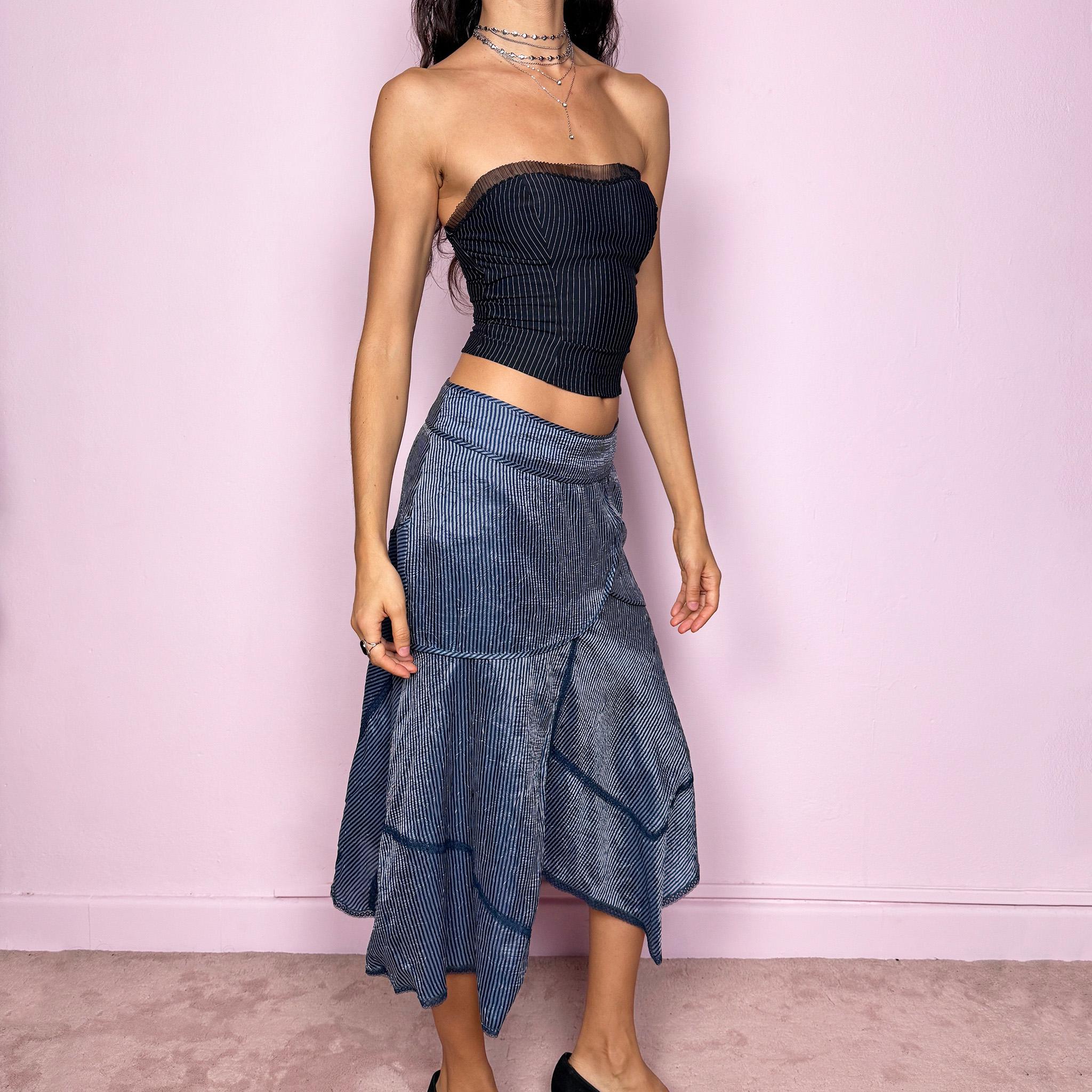 This vintage 2000s blue striped patchwork midi skirt features an asymmetric hemline, delicate lace trim details, and a side zipper closure. Lightweight and non-stretch, it offers a breezy, formal look ideal for summer styling. Can be worn low-rise for size XS or mid-rise for size S, creating an elegant and modern silhouette. Excellent vintage condition.