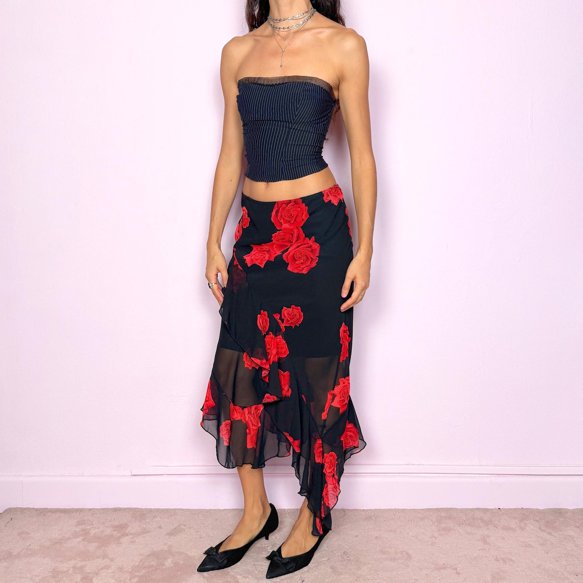 This vintage 90s black midi skirt features bold red rose floral prints, cascading ruffles, and a soft elastic waist for comfort and movement. Its romantic coquette design blends elegance and sensuality, perfect for formal events, summer nights, or evening parties. Can be worn low- or mid-rise for size L. Great vintage condition.