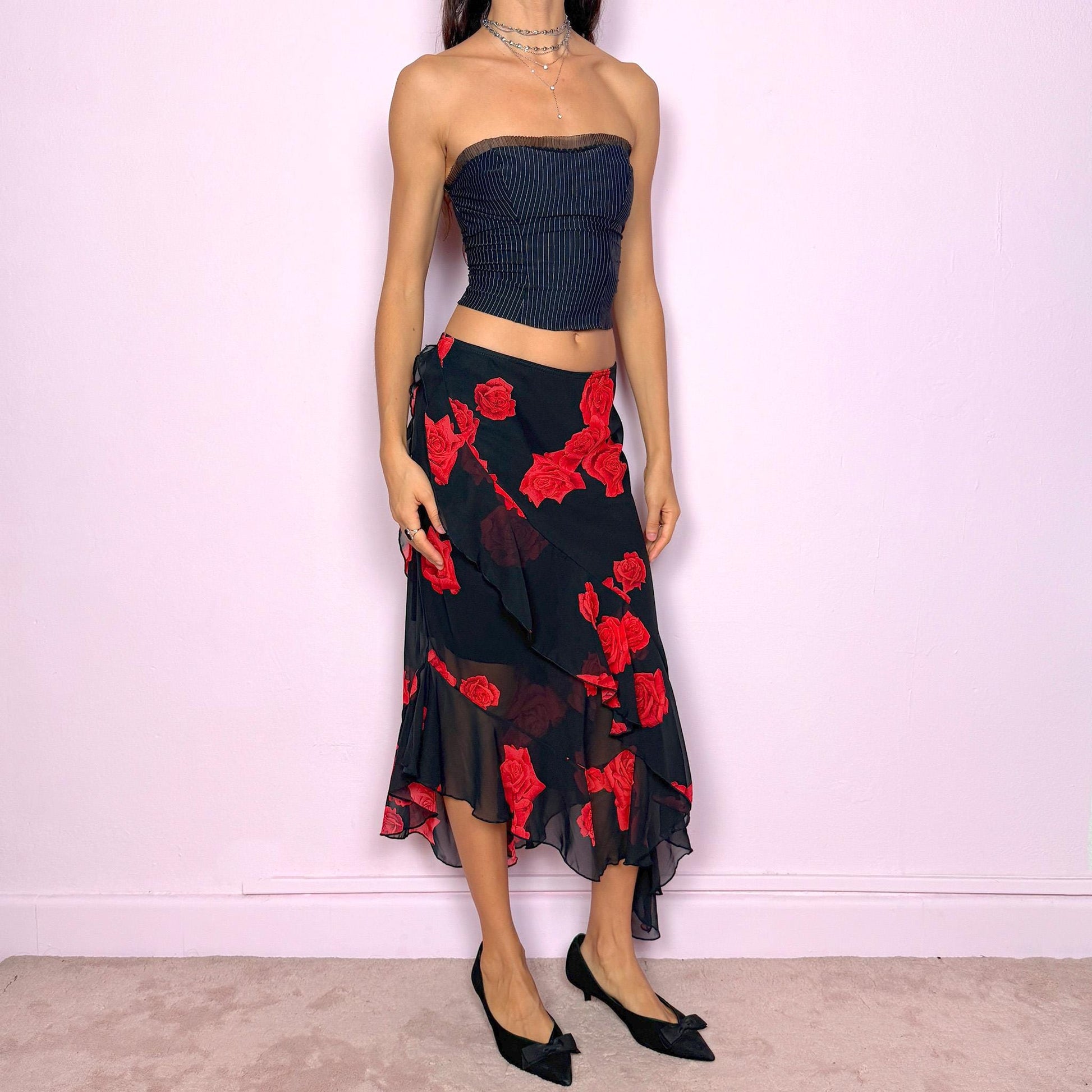 This vintage 90s black midi skirt features bold red rose floral prints, cascading ruffles, and a soft elastic waist for comfort and movement. Its romantic coquette design blends elegance and sensuality, perfect for formal events, summer nights, or evening parties. Can be worn low- or mid-rise for size L. Great vintage condition.