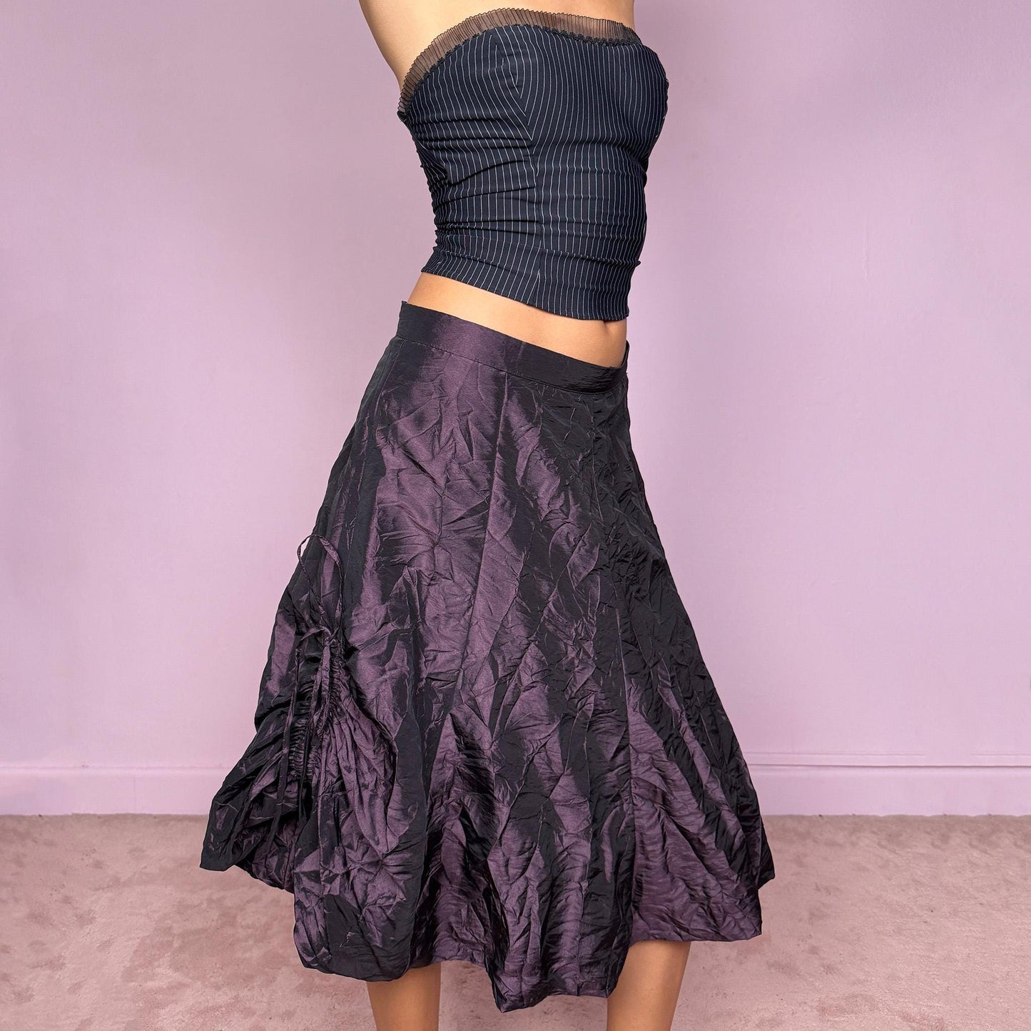 This vintage 90s dark purple iridescent midi skirt features a bubble balloon hem and adjustable ruched drawstrings at the sides, allowing for a sculptural, futuristic silhouette. Crafted from textured crinkle fabric with a back zipper closure and no stretch. A rare statement piece merging cyber, dystopian, and techwear aesthetics with Harajuku grunge edge. Can be worn high-waisted for size XL or mid-rise for size L. Excellent vintage condition.