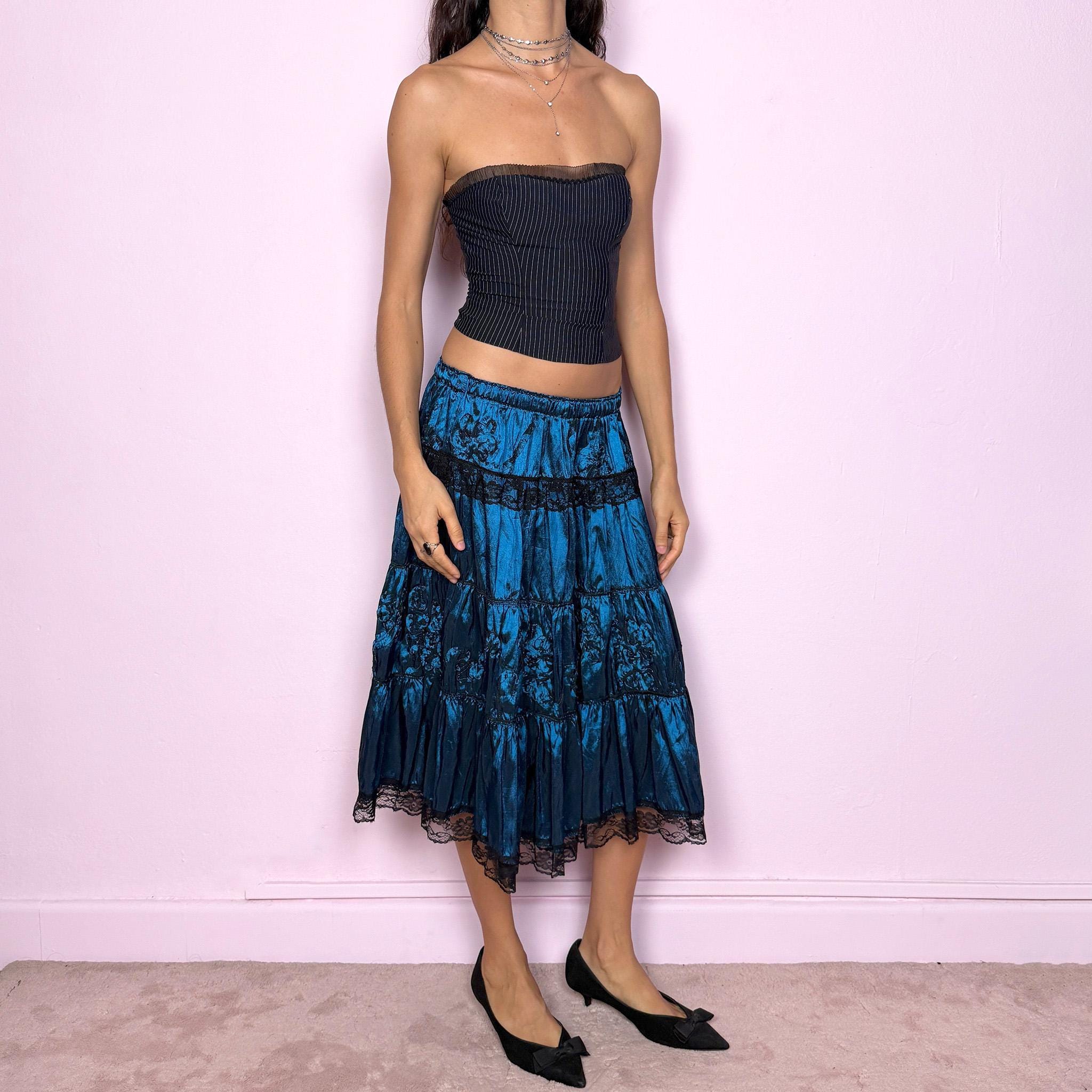 This stunning vintage 90s blue tiered midi skirt features an elastic waist, black lace trims, and delicate applique details for a dreamy, gothic silhouette. The rich sheen and romantic texture evoke dark romance and witchy elegance, perfect for formal nights, parties, or galas. Fits low-rise or high-rise for XS and S sizes. Excellent vintage condition.