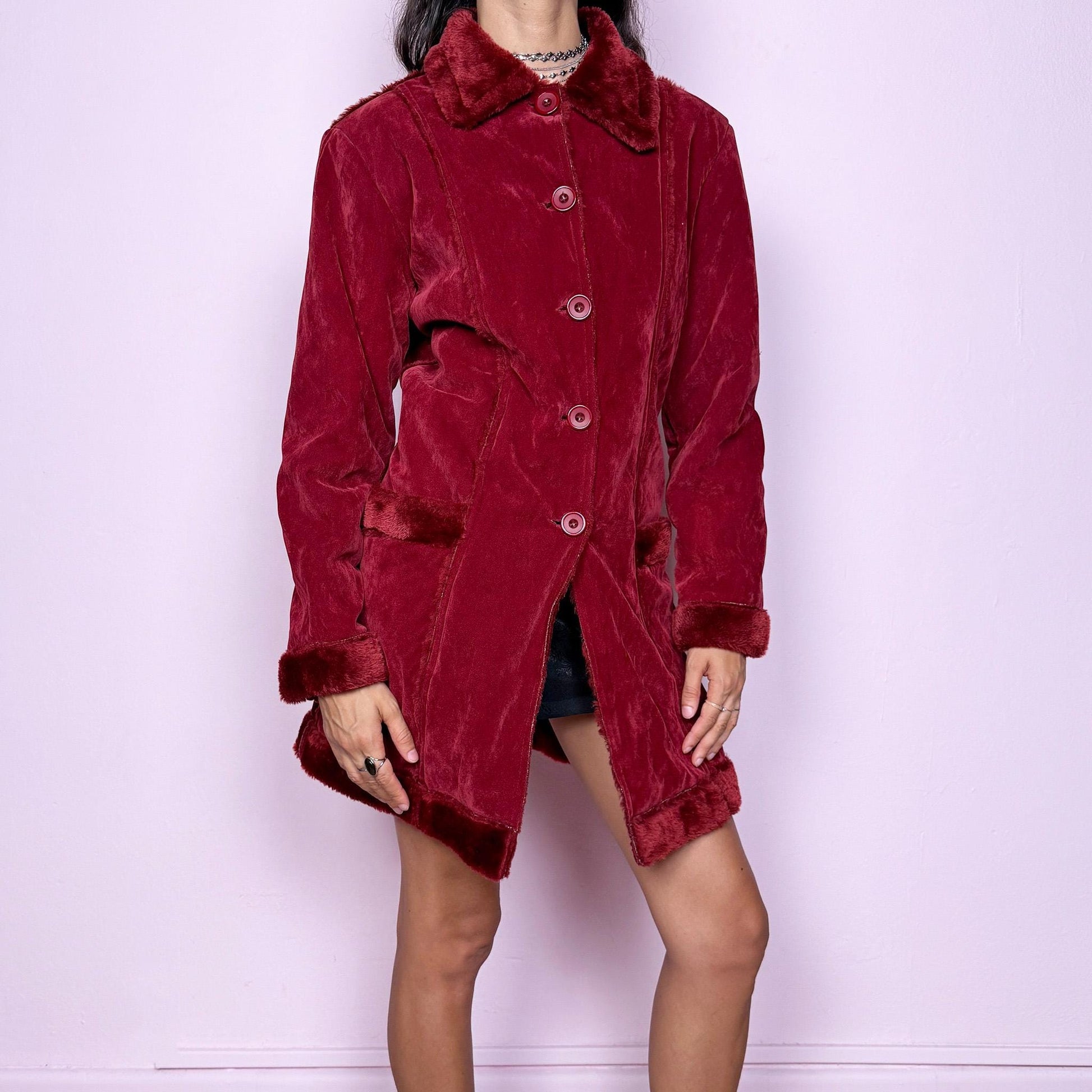 This vintage 2000s red faux suede coat features a plush faux fur lining, collar, and cuffs inspired by the iconic Penny Lane silhouette. Designed with front pockets and button closure, it captures whimsical Y2K winter charm with a boho-grunge edge, perfect for festivals or statement cold-weather styling. Made from polyester faux suede and faux fur. Great vintage condition.