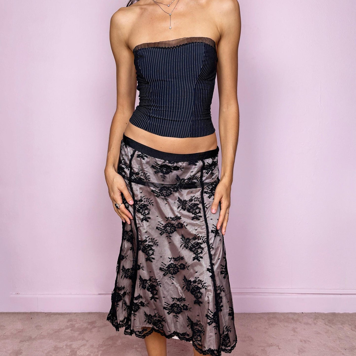 This vintage 2000s midi skirt features delicate black lace overlaying a pale pink lining, creating a stunning dark romantic contrast. Designed with a side zipper closure and no stretch, it perfectly embodies the coquette aesthetic with a touch of elegant sensuality. Ideal for office chic looks, cocktail nights, or romantic dinner dates styled with heels. Fits mid-rise for size M and low-rise for size S. Great vintage condition.