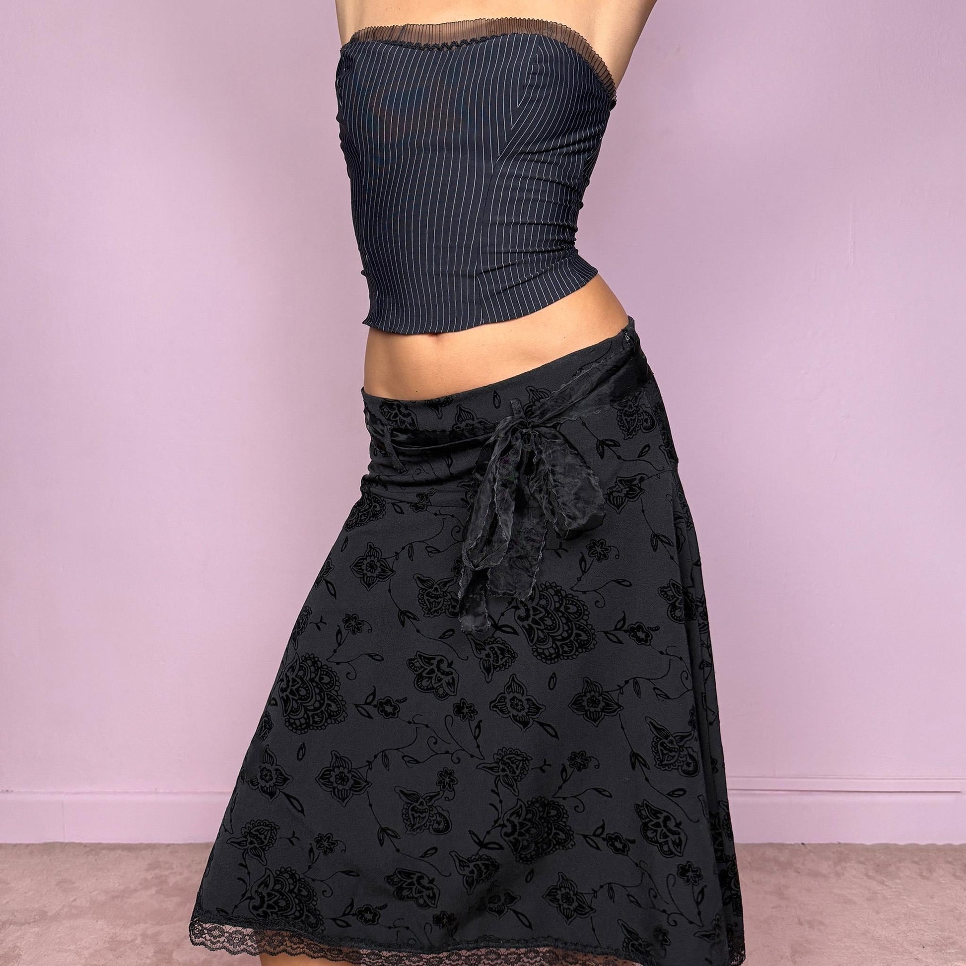 This vintage 2000s black jacquard brocade midi skirt features floral and paisley velvet details, lace trim at the hem, and a stretchy fit with side zipper closure. Made in Italy from a viscose polyester blend, it captures dark romance with a formal yet cute coquette allure. Ideal for office wear, elegant night parties, or refined events. Can be worn high/mid-rise for M size or low-rise for S size. Great vintage condition.