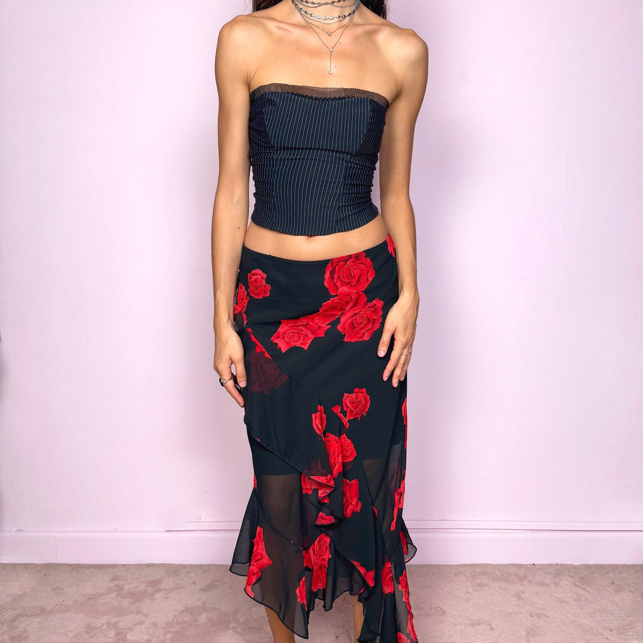 This vintage 90s black midi skirt features bold red rose floral prints, cascading ruffles, and a soft elastic waist for comfort and movement. Its romantic coquette design blends elegance and sensuality, perfect for formal events, summer nights, or evening parties. Can be worn low- or mid-rise for size L. Great vintage condition.