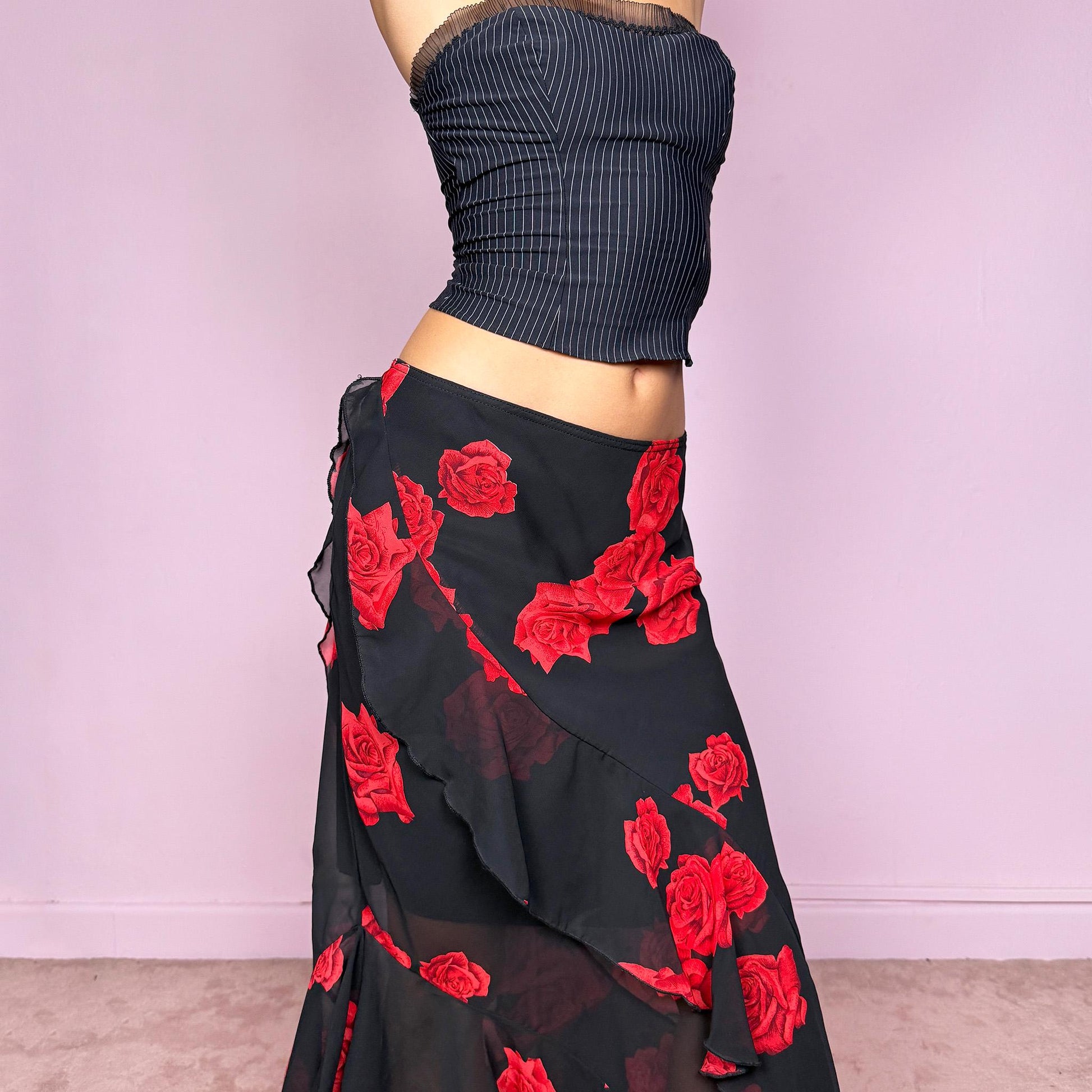 This vintage 90s black midi skirt features bold red rose floral prints, cascading ruffles, and a soft elastic waist for comfort and movement. Its romantic coquette design blends elegance and sensuality, perfect for formal events, summer nights, or evening parties. Can be worn low- or mid-rise for size L. Great vintage condition.