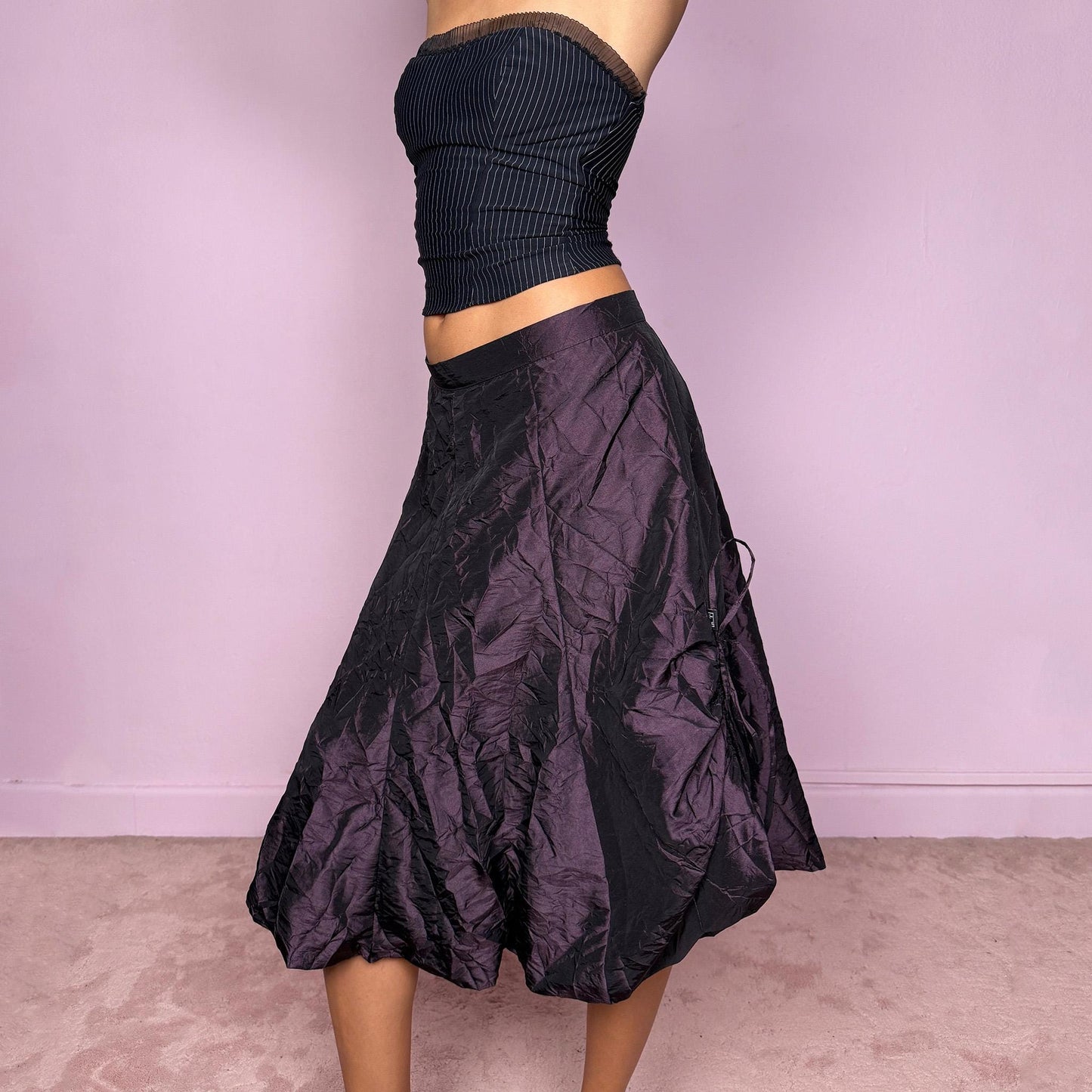 This vintage 90s dark purple iridescent midi skirt features a bubble balloon hem and adjustable ruched drawstrings at the sides, allowing for a sculptural, futuristic silhouette. Crafted from textured crinkle fabric with a back zipper closure and no stretch. A rare statement piece merging cyber, dystopian, and techwear aesthetics with Harajuku grunge edge. Can be worn high-waisted for size XL or mid-rise for size L. Excellent vintage condition.