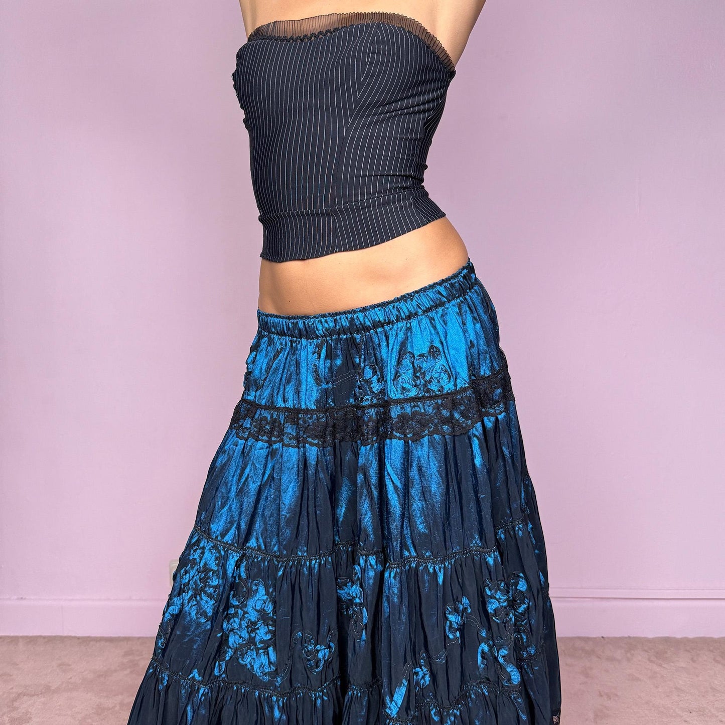 This stunning vintage 90s blue tiered midi skirt features an elastic waist, black lace trims, and delicate applique details for a dreamy, gothic silhouette. The rich sheen and romantic texture evoke dark romance and witchy elegance, perfect for formal nights, parties, or galas. Fits low-rise or high-rise for XS and S sizes. Excellent vintage condition.