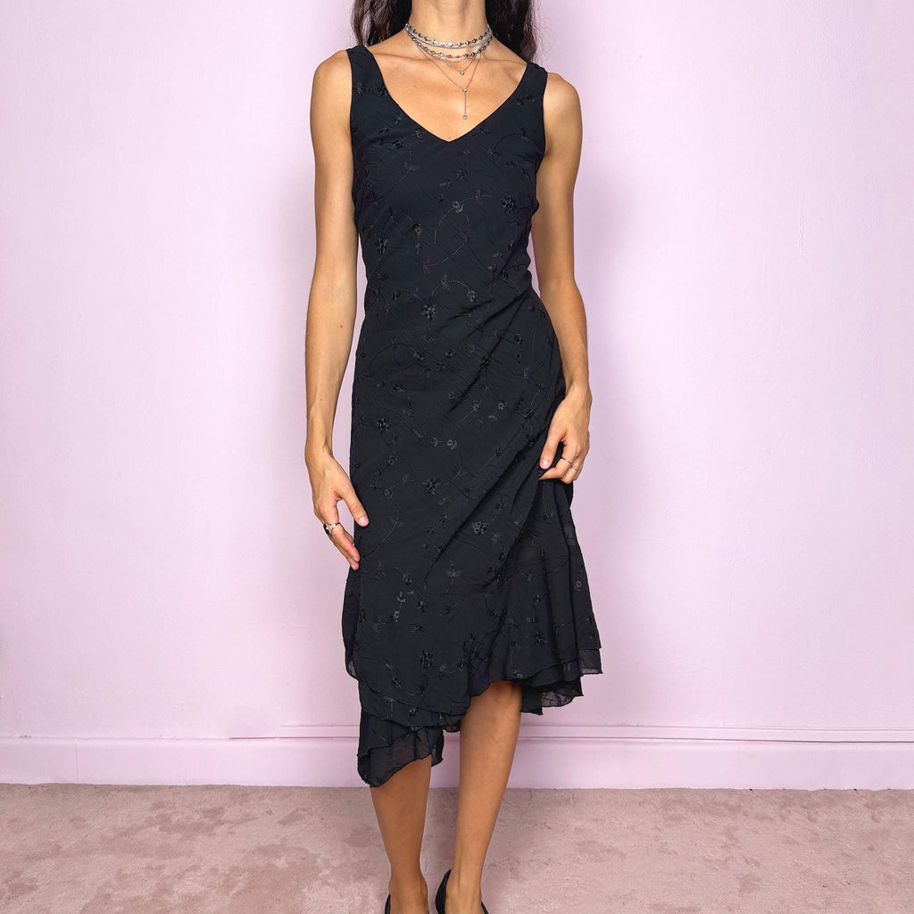 Romantic vintage 2000s black midi dress featuring delicate floral embroidery, a sleeveless cut, a V-neckline and an asymmetrical layered ruffle hem. The slightly stretchy fabric offers a comfortable, flattering fit with a minimal yet elegant look, perfect for a summer night event. Made in Spain from polyester. Excellent vintage condition.
