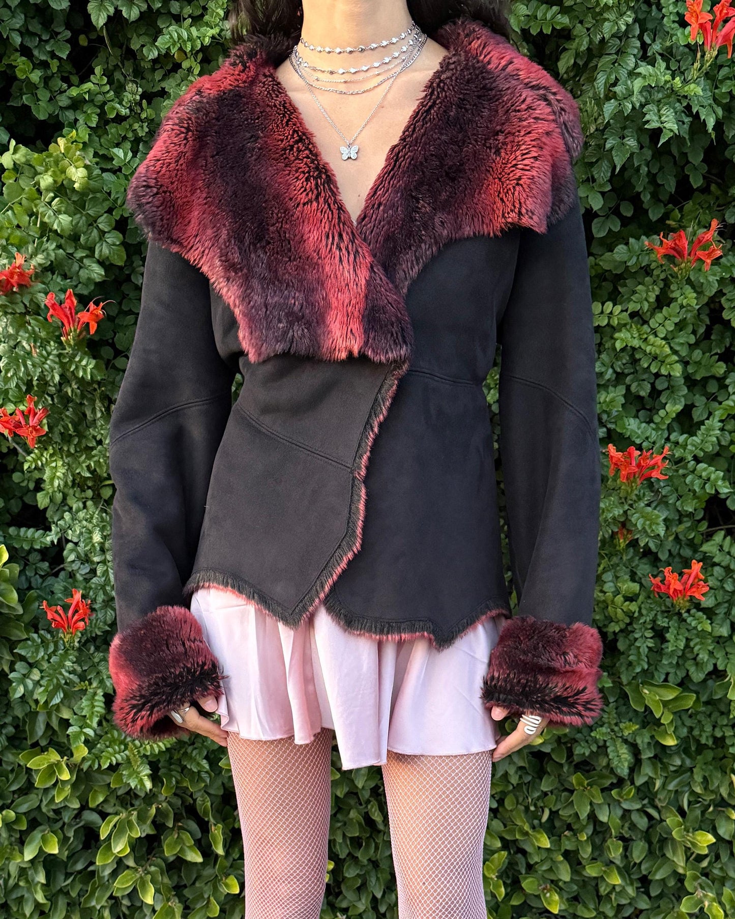 Stunning vintage 2000s Penny Lane–style jacket featuring a black faux-suede exterior with full red-and-black faux-fur lining. Designed with a dramatic faux-fur trimmed collar and cuffs, angled panel construction and a single button closure for a fitted silhouette. The polyester–acrylic blend has no stretch and provides a warm, cozy feel ideal for winter layering. A French-design cyber streetwear and grunge statement coat perfect for night outings and bold Y2K styling.