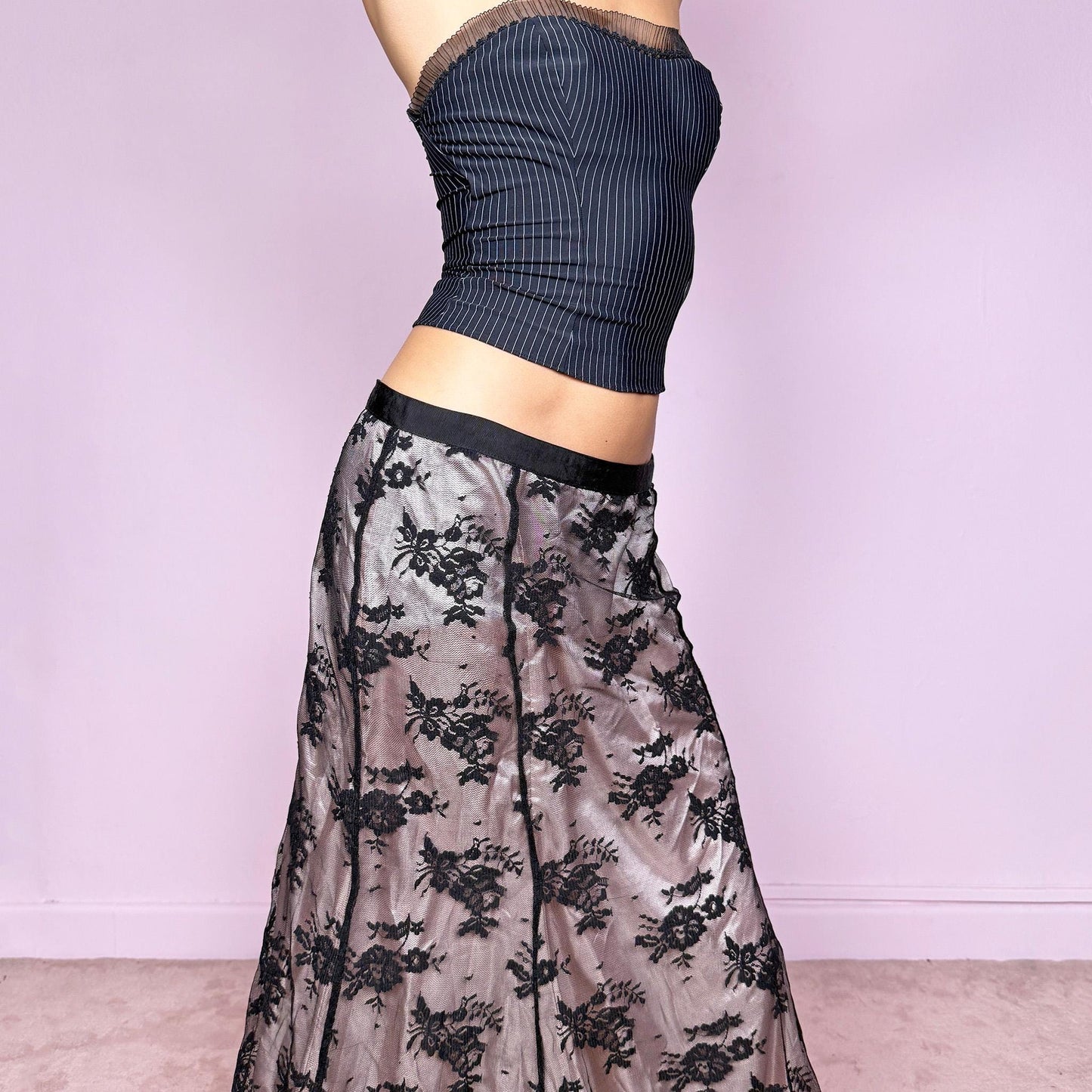 This vintage 2000s midi skirt features delicate black lace overlaying a pale pink lining, creating a stunning dark romantic contrast. Designed with a side zipper closure and no stretch, it perfectly embodies the coquette aesthetic with a touch of elegant sensuality. Ideal for office chic looks, cocktail nights, or romantic dinner dates styled with heels. Fits mid-rise for size M and low-rise for size S. Great vintage condition.