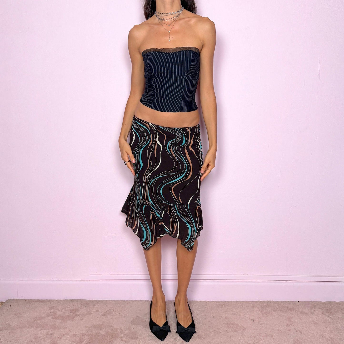 This vintage 2000s playful dark brown trumpet midi skirt features an asymmetrical handkerchief hem, wave-striped print, and soft elastic waist. A fluid, modern Y2K silhouette for city girls embracing statement summer parties or expressive everyday looks. Effortlessly versatile, it can be worn high waisted or low rise for both size XS and S. Made from viscose polyester blend. Excellent vintage condition.