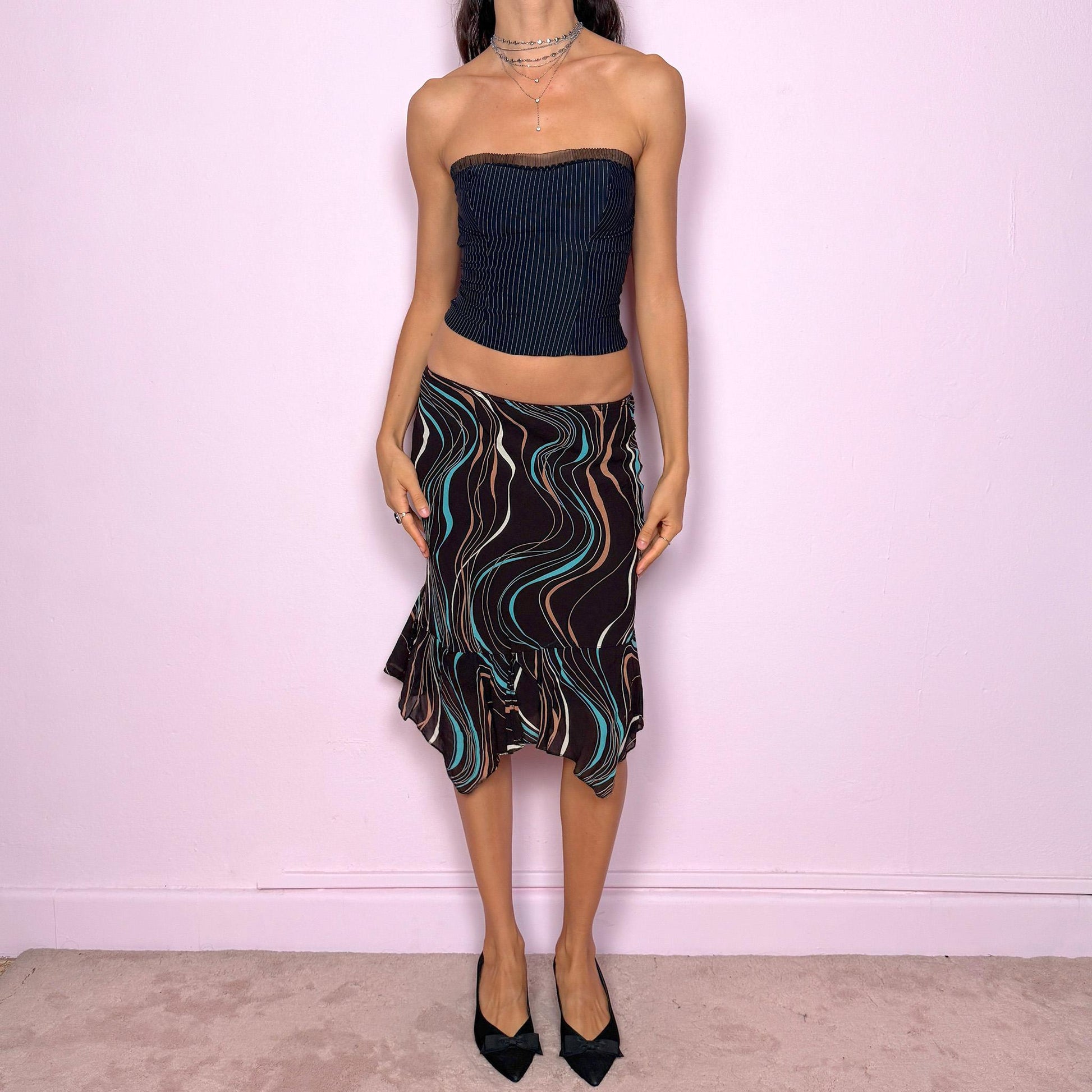 This vintage 2000s playful dark brown trumpet midi skirt features an asymmetrical handkerchief hem, wave-striped print, and soft elastic waist. A fluid, modern Y2K silhouette for city girls embracing statement summer parties or expressive everyday looks. Effortlessly versatile, it can be worn high waisted or low rise for both size XS and S. Made from viscose polyester blend. Excellent vintage condition.