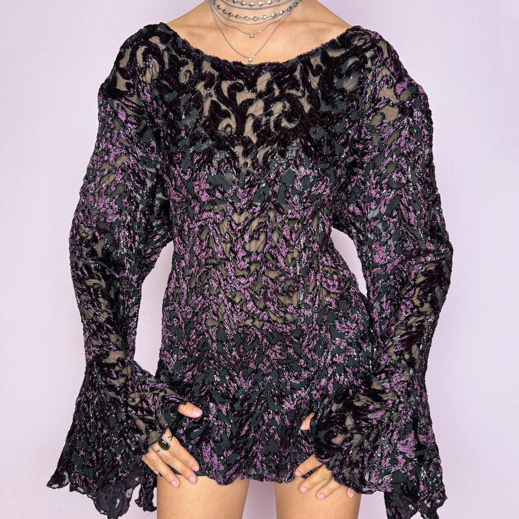 This vintage 2000s purple and black devoré velvet top delivers a dark romantic, witchy, goth aesthetic with a fitted bodice, sheer burnout pattern, metallic threads, asymmetric bell sleeves, and a flared hem. Ideal for evening styling, festivals, and statement layering. An archival French piece with a stretchy finish for comfortable wear. Excellent vintage condition.
