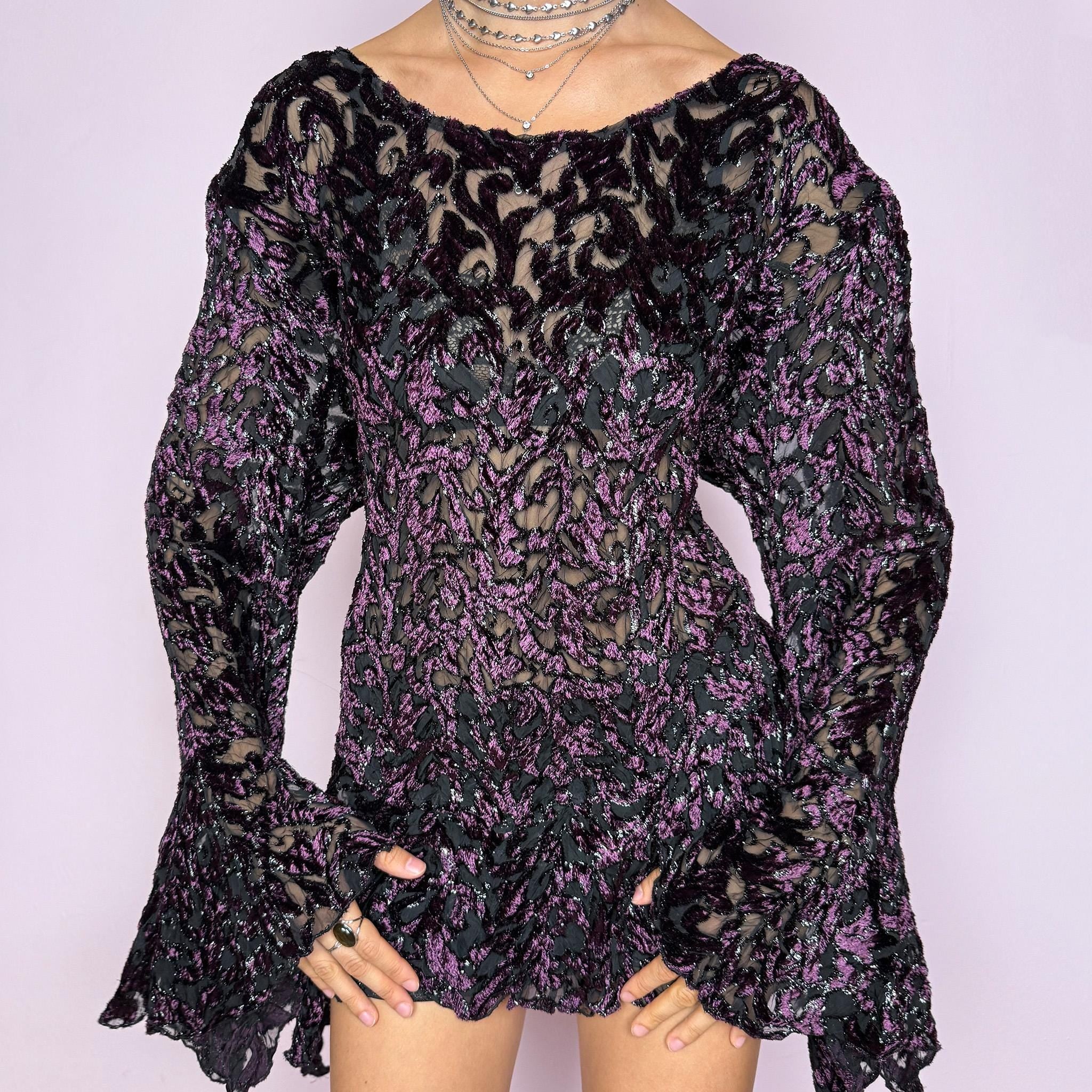 This vintage 2000s purple and black devoré velvet top delivers a dark romantic, witchy, goth aesthetic with a fitted bodice, sheer burnout pattern, metallic threads, asymmetric bell sleeves, and a flared hem. Ideal for evening styling, festivals, and statement layering. An archival French piece with a stretchy finish for comfortable wear. Excellent vintage condition.