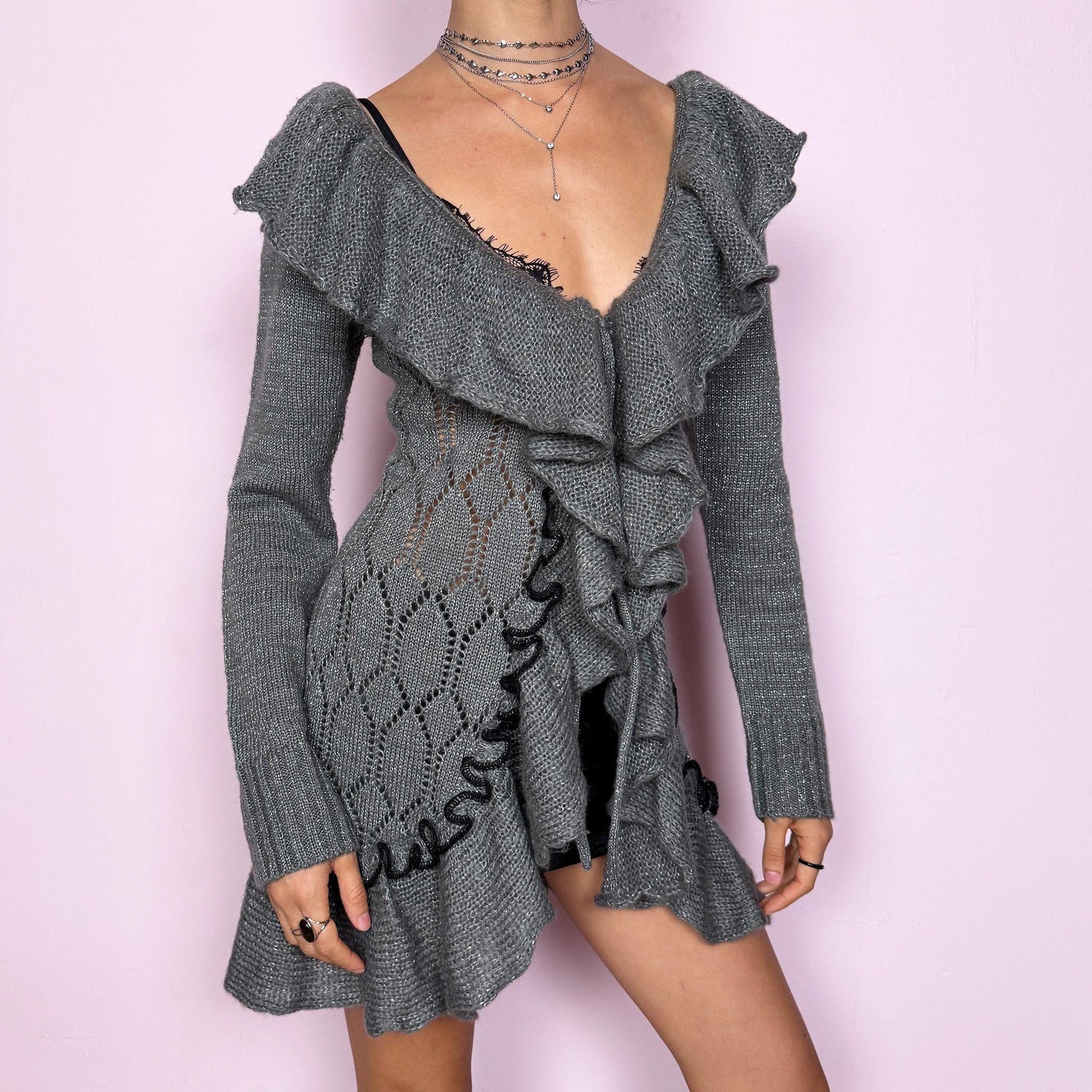 This romantic vintage 2000s gray longline open-knit cardigan features a dramatic ruffle neckline, ruffled hem, and a tie-front closure. The soft, draped silhouette and textured open-knit pattern create a whimsical coquette feel, ideal for autumn layering, winter fairycore styling, or cozy everyday outfits. Made from a stretchy acrylic and mohair blend. Great vintage condition.