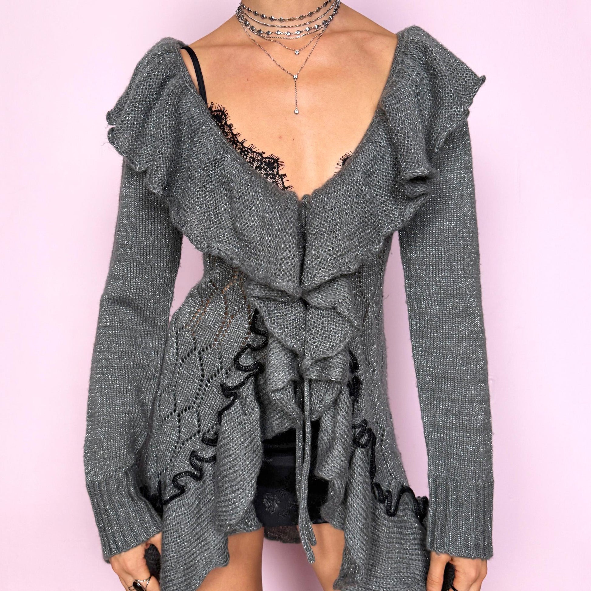 This romantic vintage 2000s gray longline open-knit cardigan features a dramatic ruffle neckline, ruffled hem, and a tie-front closure. The soft, draped silhouette and textured open-knit pattern create a whimsical coquette feel, ideal for autumn layering, winter fairycore styling, or cozy everyday outfits. Made from a stretchy acrylic and mohair blend. Great vintage condition.